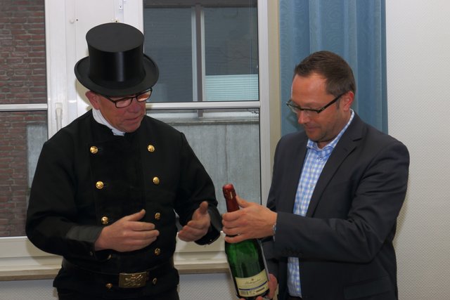 Josef van Nahmen überreicht Bürgermeister Thomas Görtz eine Sekt nachträglich zum Jahreswechsel