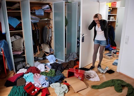 Symbolbild Einbruch. Junge Frau entdeckt einen Wohnungseinbruch, durchwuehlter Schrank. Einbrecher haben Wertgegenstaende in einem Kleiderschrank gesucht und ein Chaos hinterlassen. Schmuckschatulle ausgeräumt, Geldkassette aufgebrochen, Dokumentenkassette druchsucht.