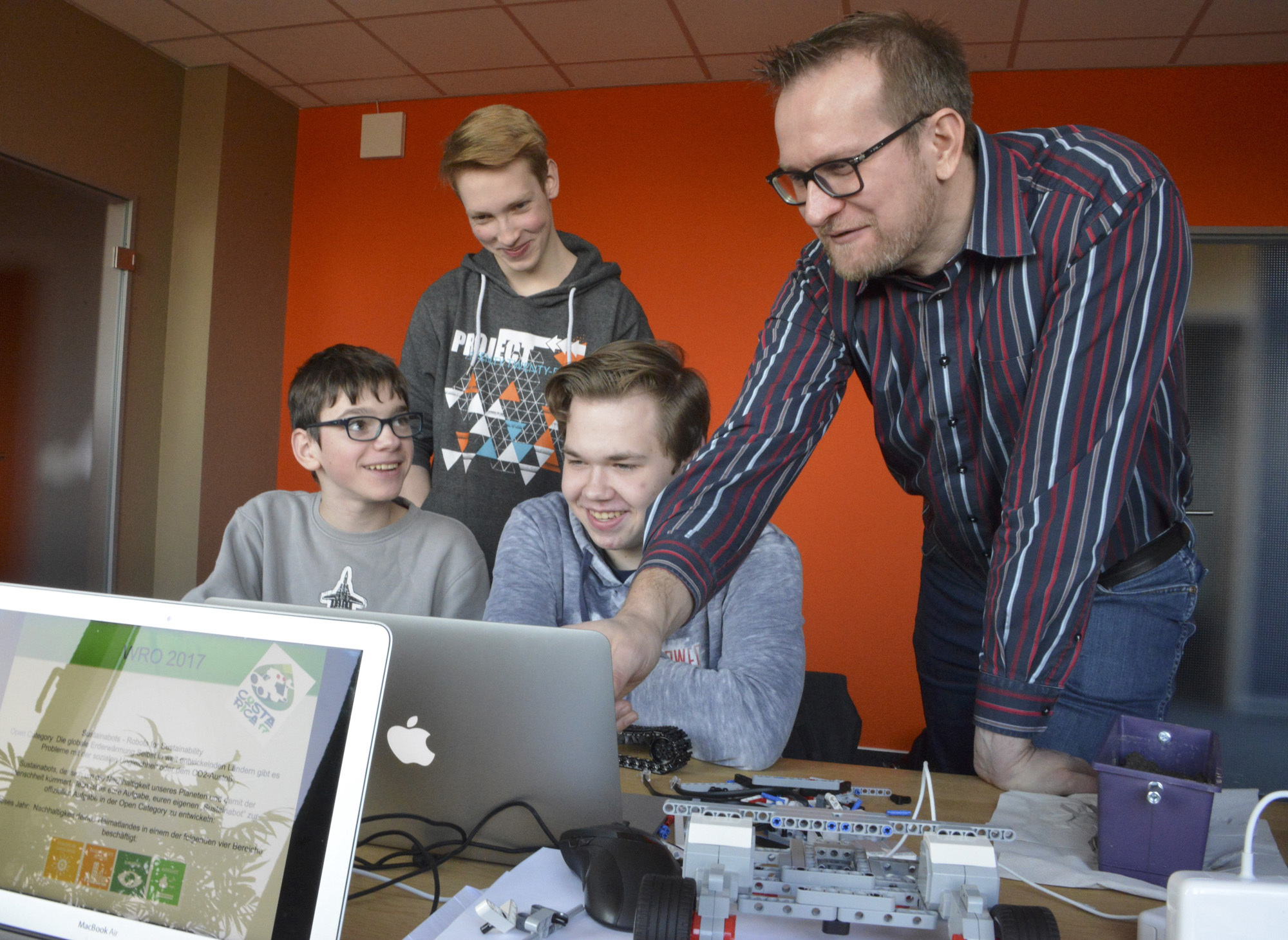 Dirk Starke unterstützt Sascha, Cedrik und René bei der Programmierung ihres Roboters.