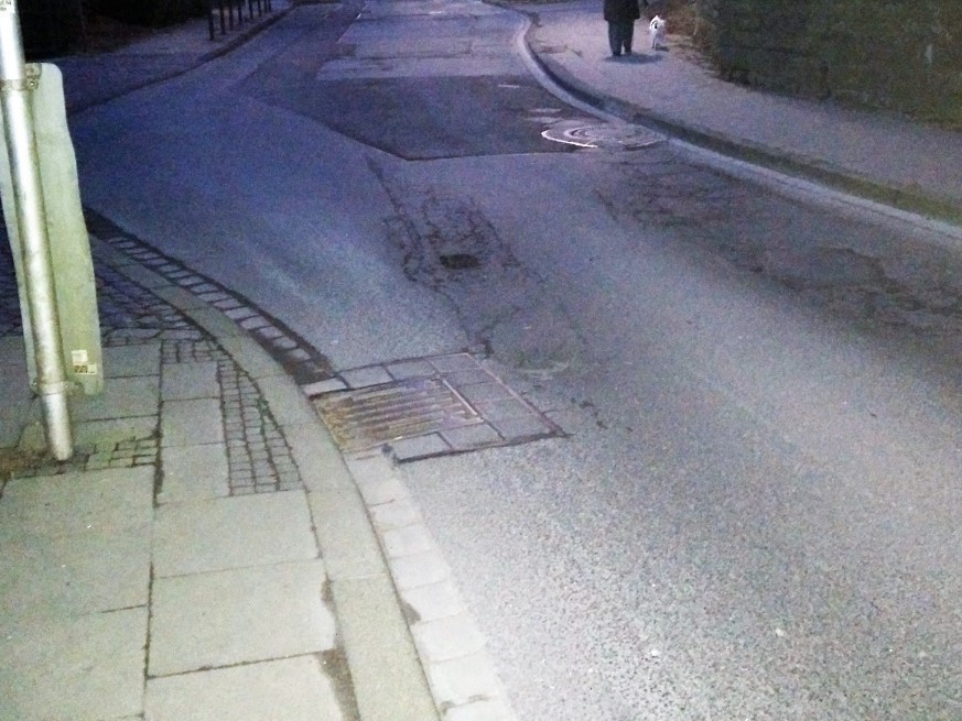 Hier ist die Straßendecke ein Stück abgesackt, hier sammelt sich das Regenwasser.