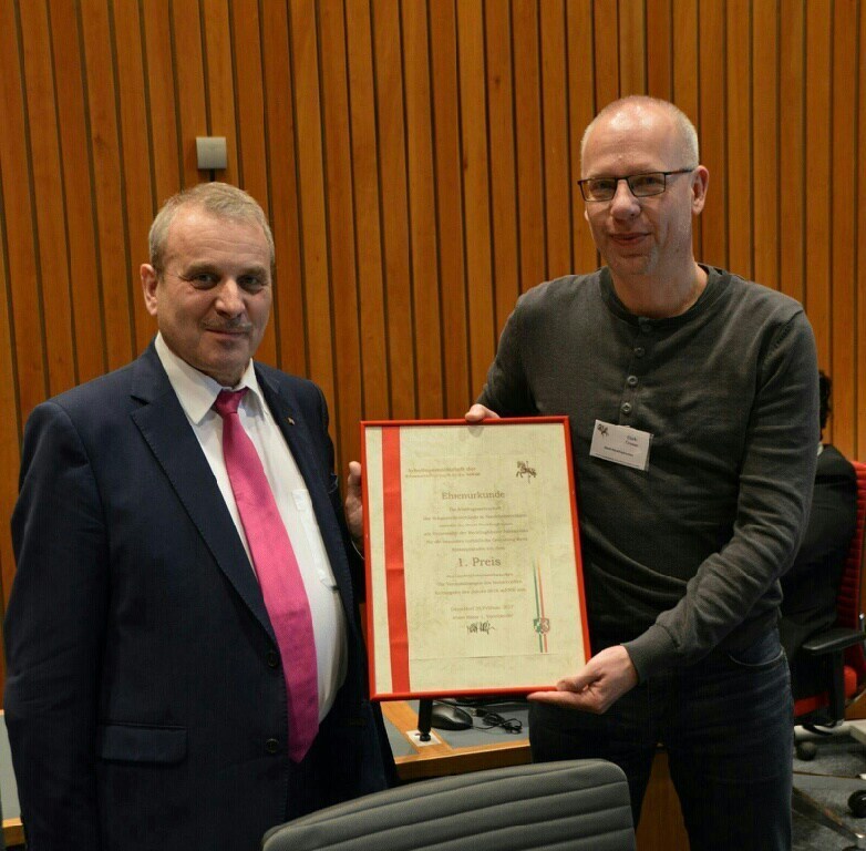 Albert Ritter (l., Erster Vorsitzender der Arbeitsgemeinschaft der Schaustellerverbände in Nordrhein-Westfalen) überreicht die Ehrenurkunde an Dirk Treese (Sachgebietsleiter Gewerbeangelegenheiten). Fotos: Stadt
