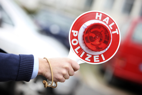 Polizei, Zivilwagen, Polizist haelt ein Fahrzeug mit einer Anhaltekelle an. Symbolbild.