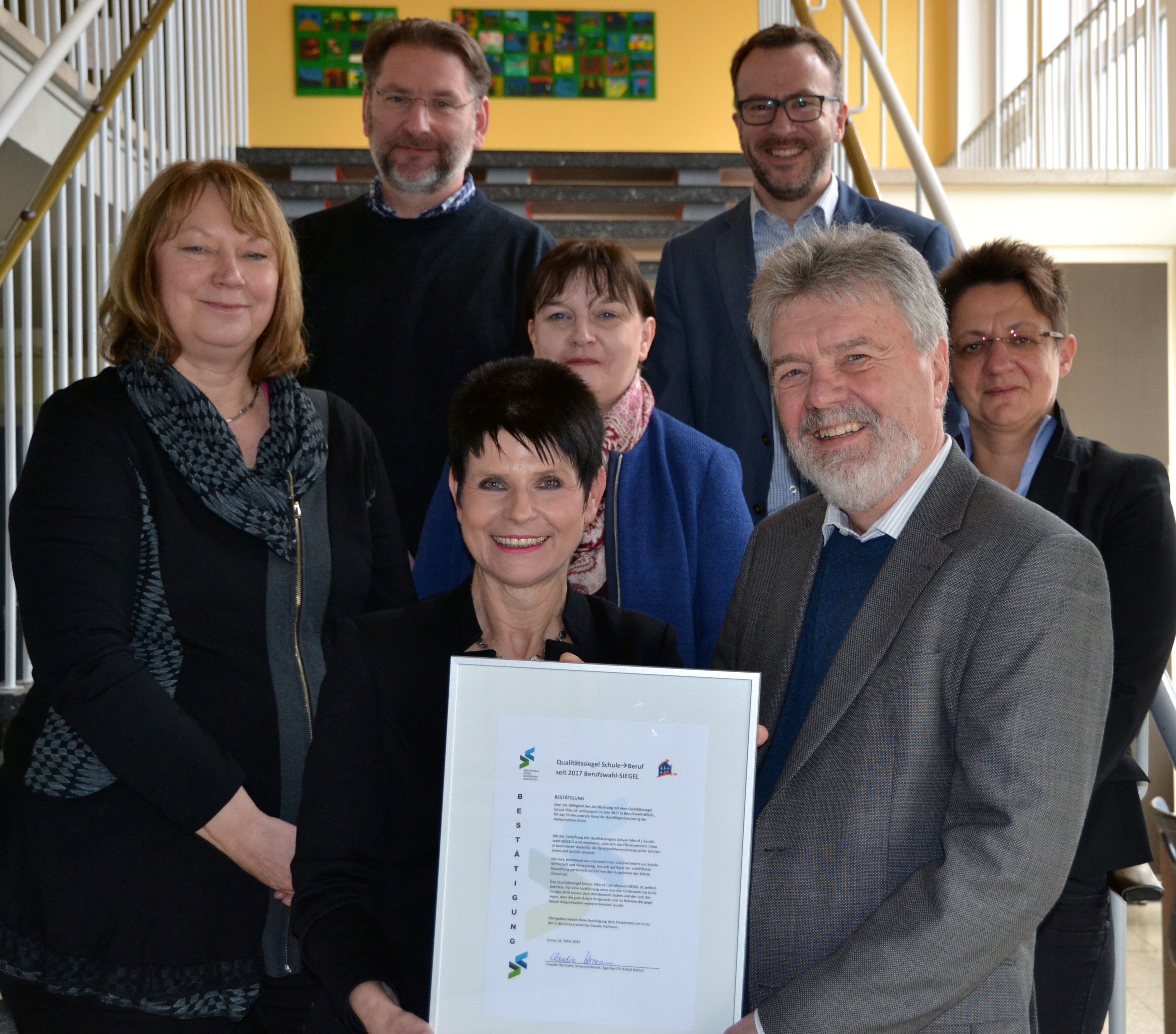 Die Juryvorsitzende Claudia Hermsen (vordere Reihe links) überreichte die Urkunde an Schulleiter Günter Michel (vorderer Reihe rechts).
