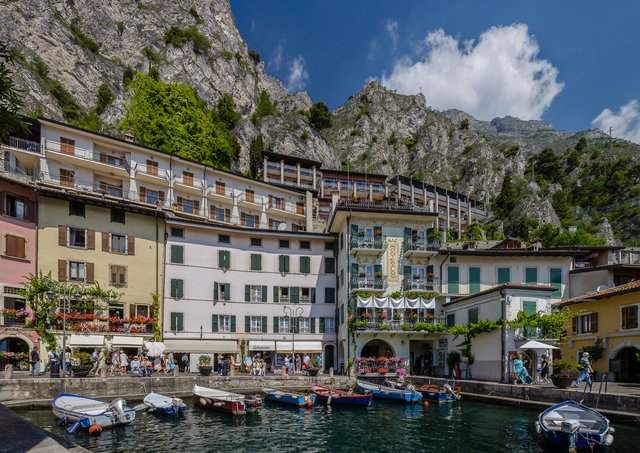 Hafen mit Fischerbooten und Häuserzeilen vor den steilen Felswänden