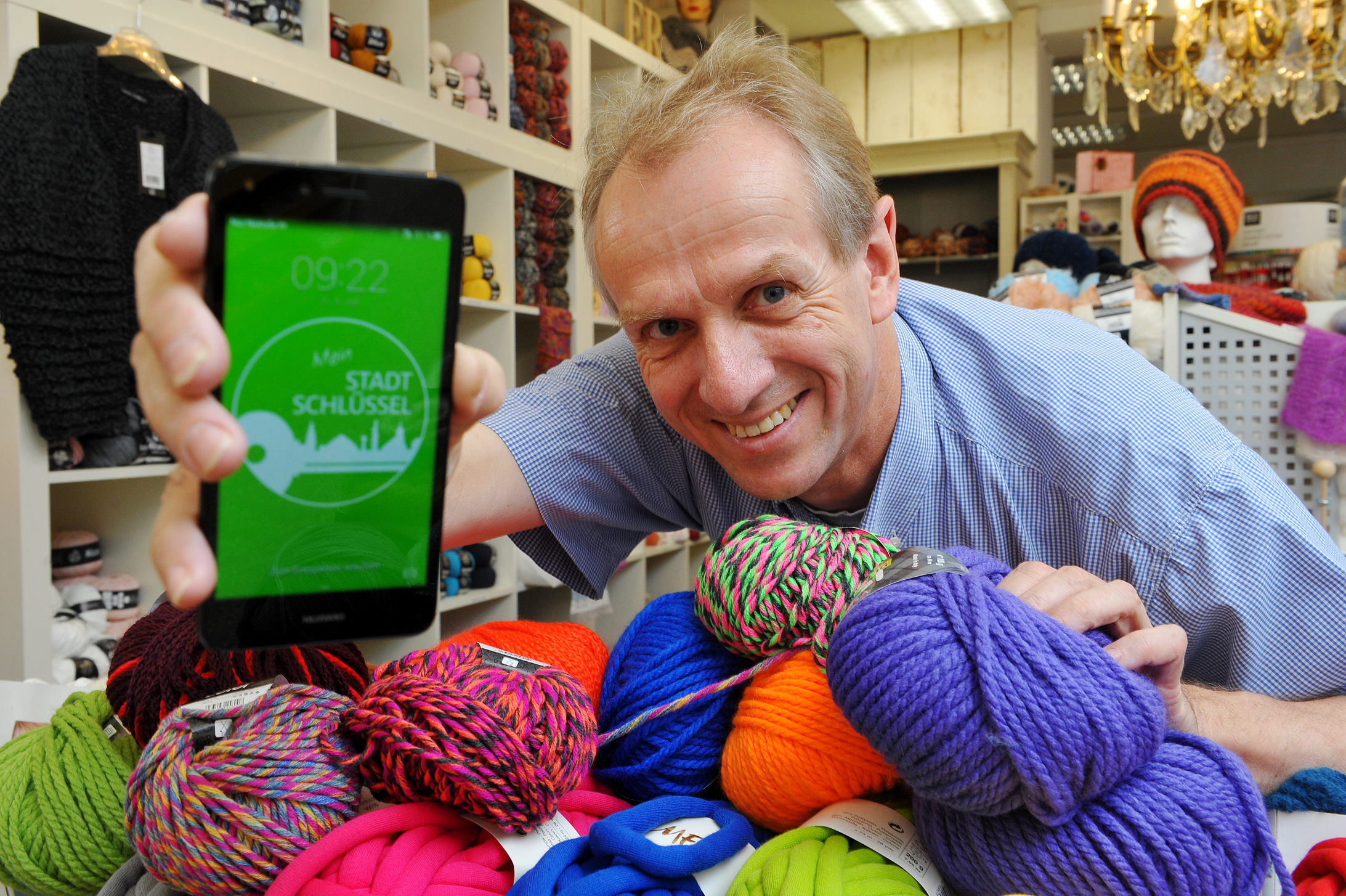 In Langenfeld möchte man für die Zukunft des Einkaufens gewappnet sein. Andreas Pollok (Kreativhaus Pollok an der Hauptstraße) hat als erstes inhabergeführtes Geschäft in Deutschland überhaupt seine Produkte bei Googles neuem Suchdienst „Google Local Inventory Ads“ gelistet. Auf dem Smartphone ist das Symbol des neuen „Stadtschlüssels“ zu sehen. Mit diesem können die Kunden demnächst bei Einkäufen Bonus-Punkte sammeln und diese dann zum Beispiel zur Bezahlung der Parkkosten nutzen. Foto: de Clerque