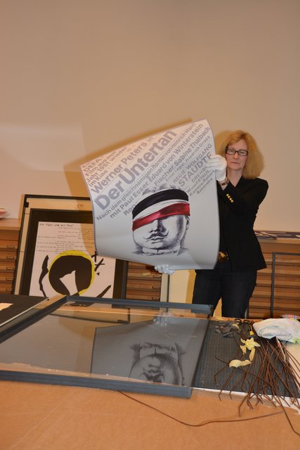 Christiane van Haaren rahmt eines der Plakate von Grüttner. Foto: Jörg Terbrüggen