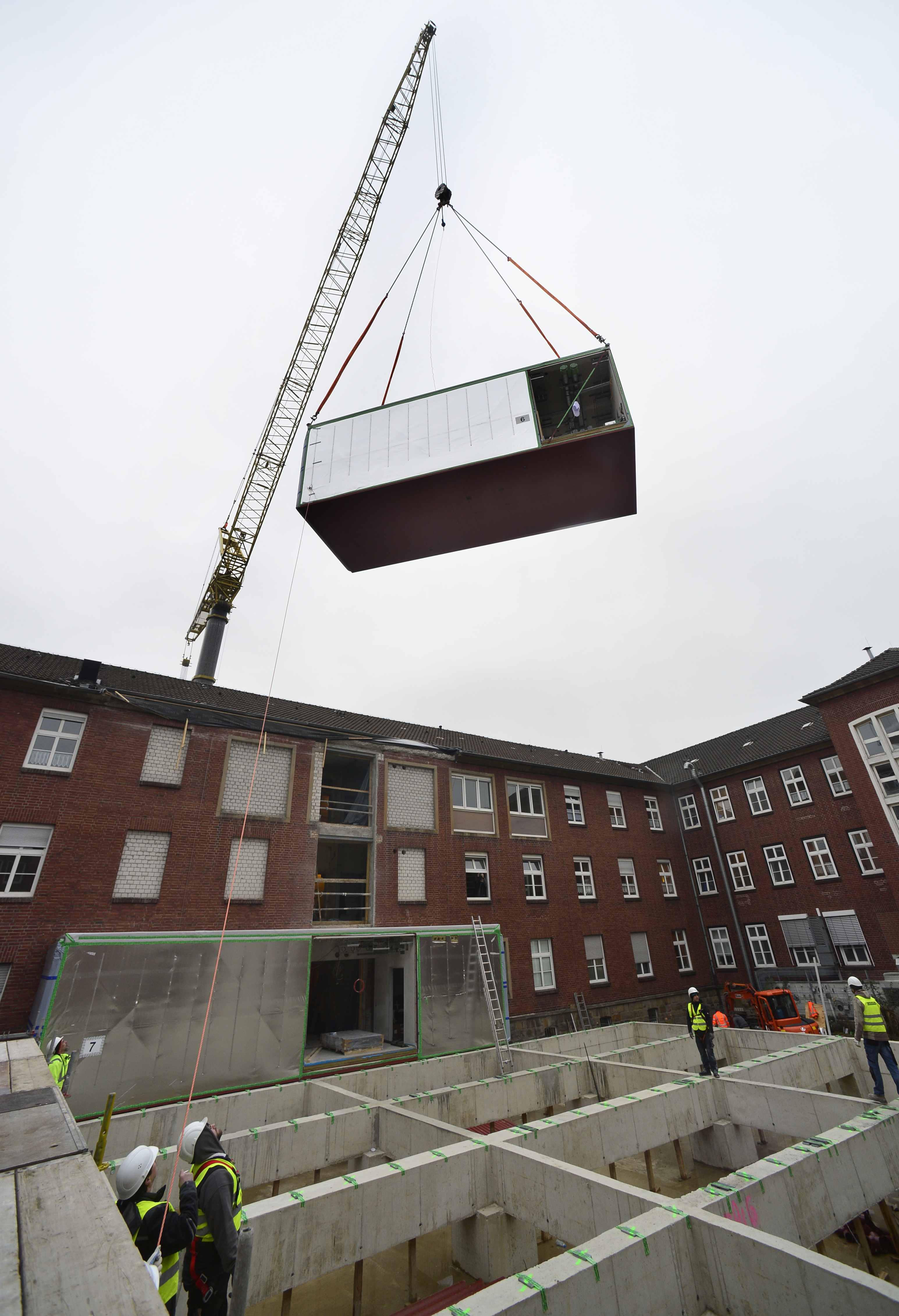 Die Baumodule schweben über den Altbau in den Neubau ein. Fotos: Braczko