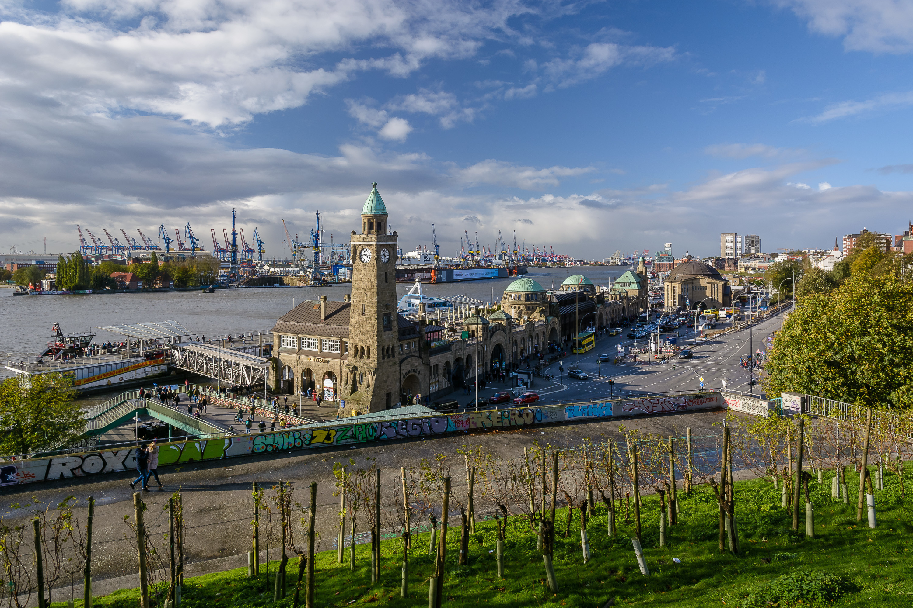 Das klassische Postkartenmotiv ist der Blick vom "Stintfang" auf die St.Pauli Landungsbrücken mit dem prägnanten Uhren- und Pegelturm und dem dahinter erkennbaren Hafen. Im Vordergrund einer der nördlichsten "Weinberge" Deutschlands.