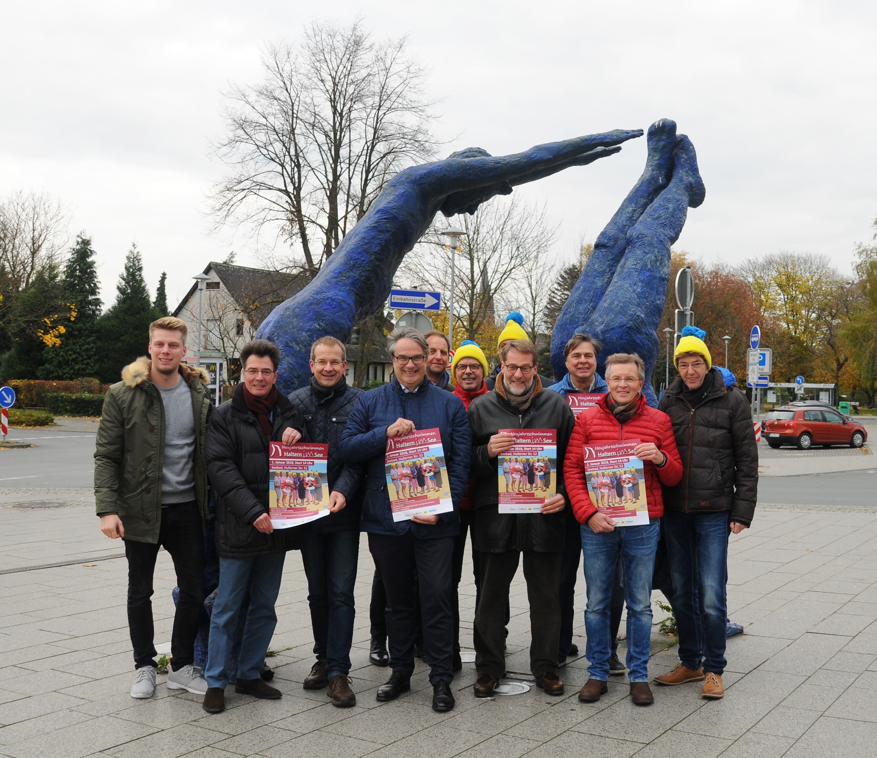 Carsten Schier und Dr Bernhard Klocke von den Halterner Stadtwerken mit ihrem Team vor der Skulptur der Taucher, die als Vorlage für das Logo des Neujahrsschwimmens diente.