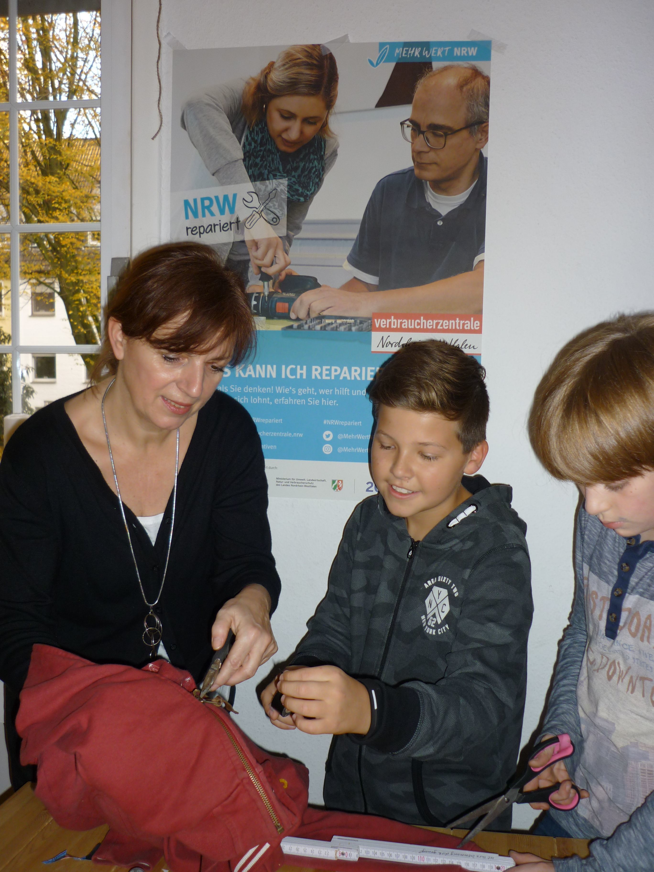 Reparatur-Workshop : Jutta Eickelpasch erklärt Tobi (12) und Josch (11) wie sie den kaputten Reißverschluss an der Winterjacke reparieren können.