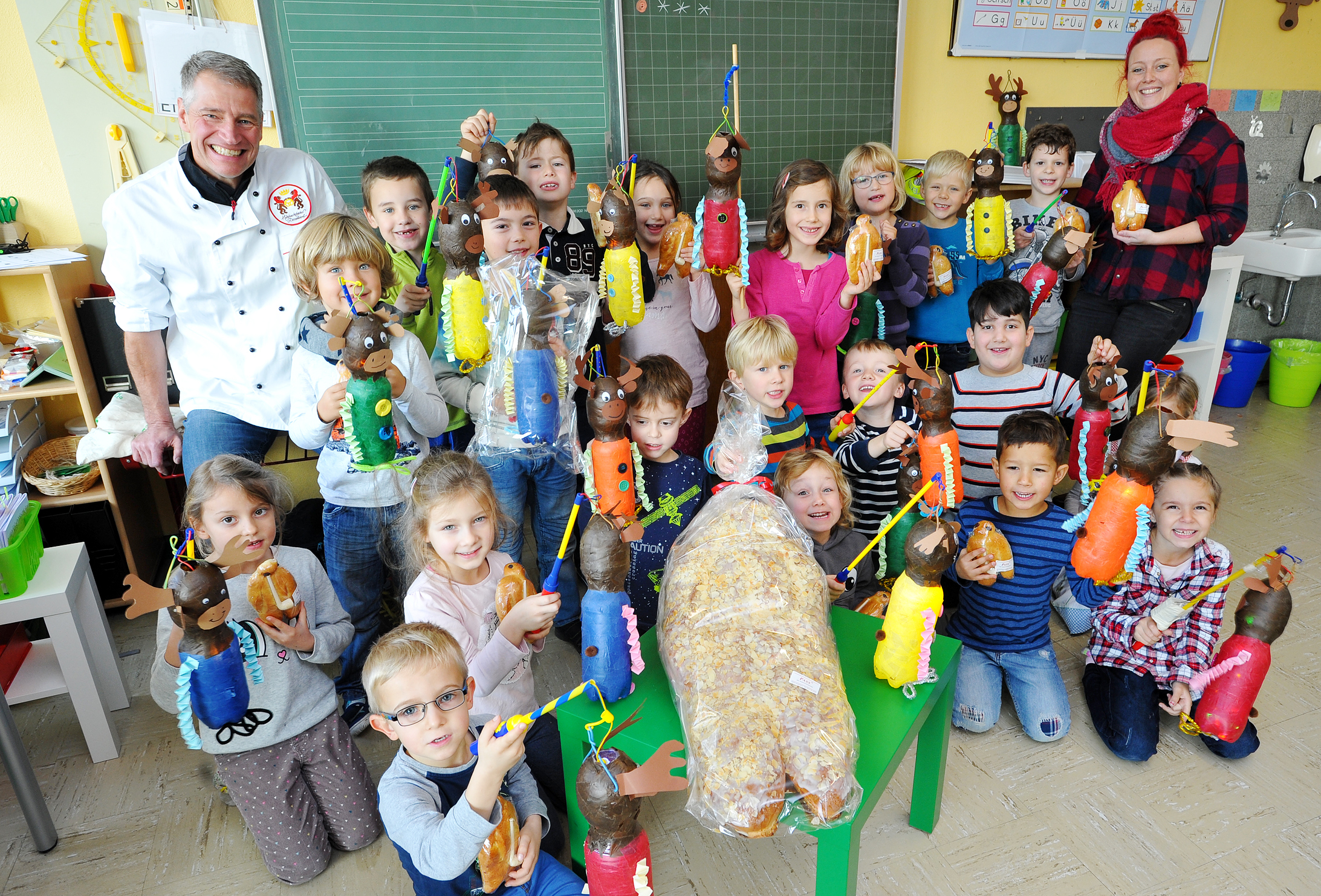 Bäckermeister Christoph Pass überreichte den Kindern der Grundschule Gieslenberg die Weckmänner persönlich. Sie sind Belohnung für ihre schönen Elch-Laternen. Klassenlehrerin Corinna Kurth ist stolz auf ihre Schülerinnen und Schüler. Foto: Michael de Clerque