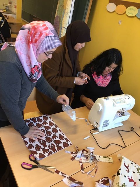 Die Frauen helfen sich gegenseitig bei der Näharbeit.