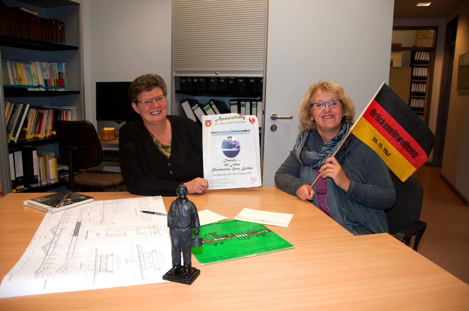 Eila Braam (l.) mit Ausstellungsplakat und Tina Oostendorp (r.) mit Original-Fahne zur Brückeneinweihung.
(Foto: Dirk Kleinwegen)