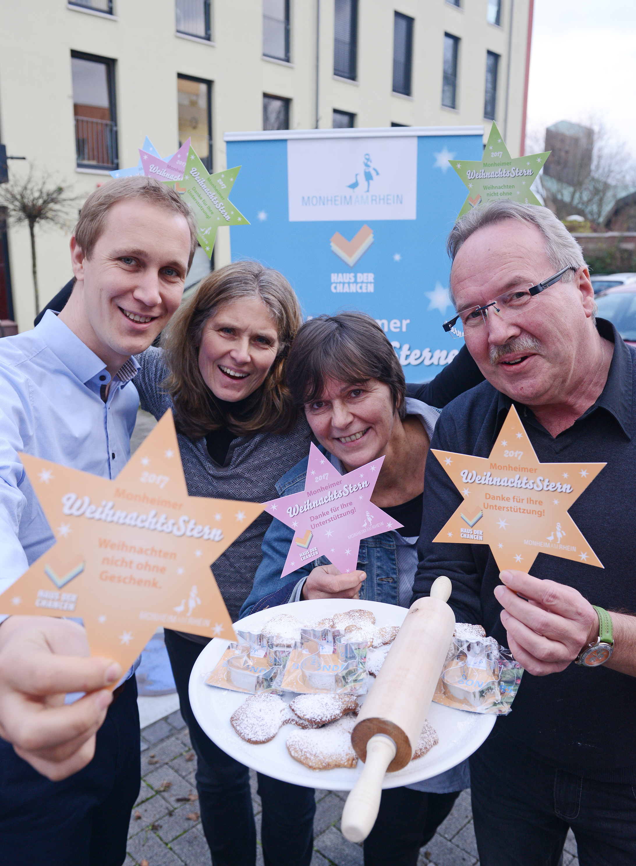 Bürgermeister Daniel Zimmermann, die Leiterin des Bereichs Kinder, Jugend und Familie Simone Feldmann, Mo.Ki-Koordinatorin Inge Nowak und Michael Woloschenik vom Beratungscentrum haben die neuen Plätzchenausstecher bereits ausprobiert und werben vor dem Haus der Chancen gemeinsam für die Aktion "Monheimer Weihnachtssterne".