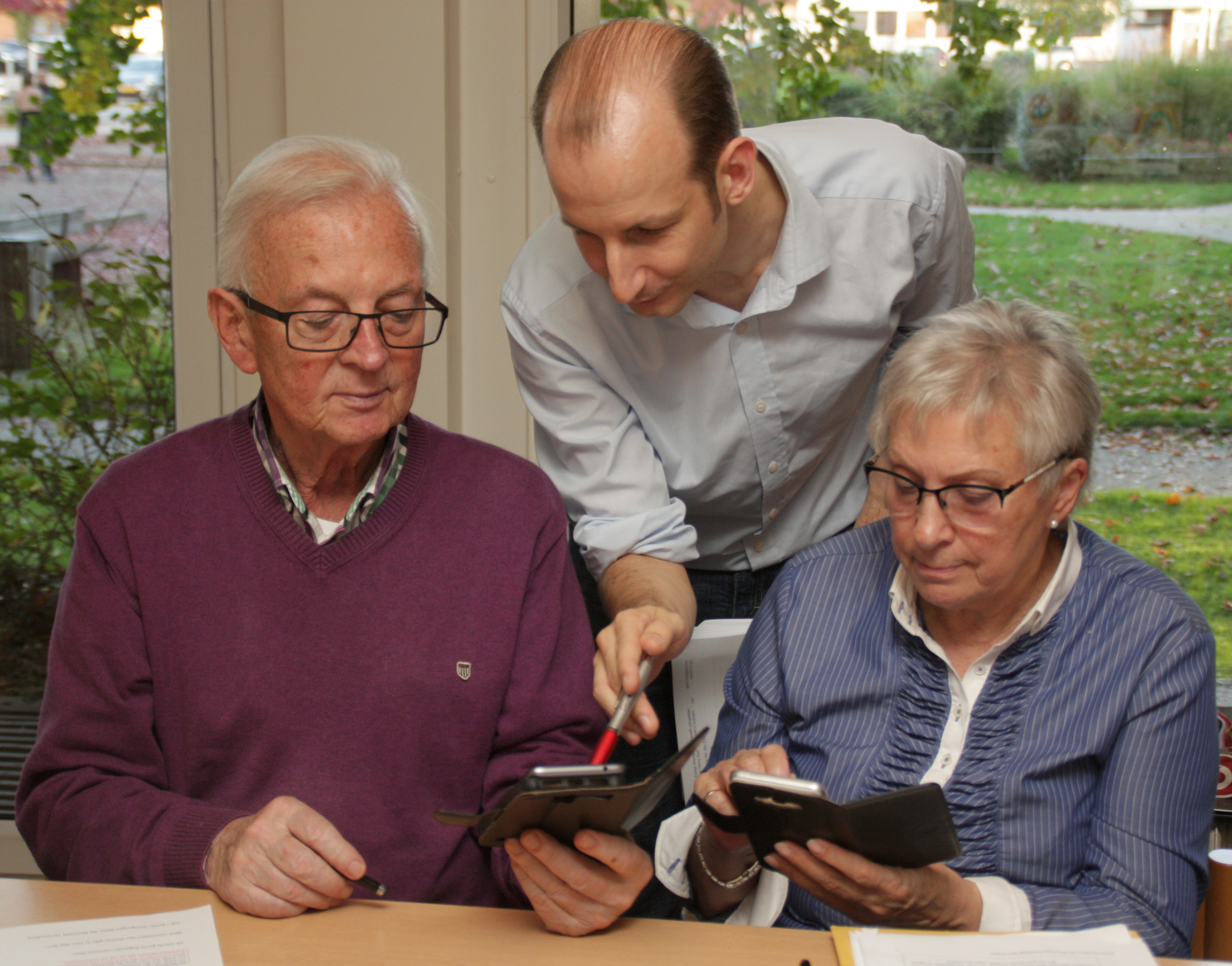 Kursleiter Georg Stark (Mitte) erklärt Senioren im Albert-Schmidt-Haus den Umgang mit dem Smartphone.