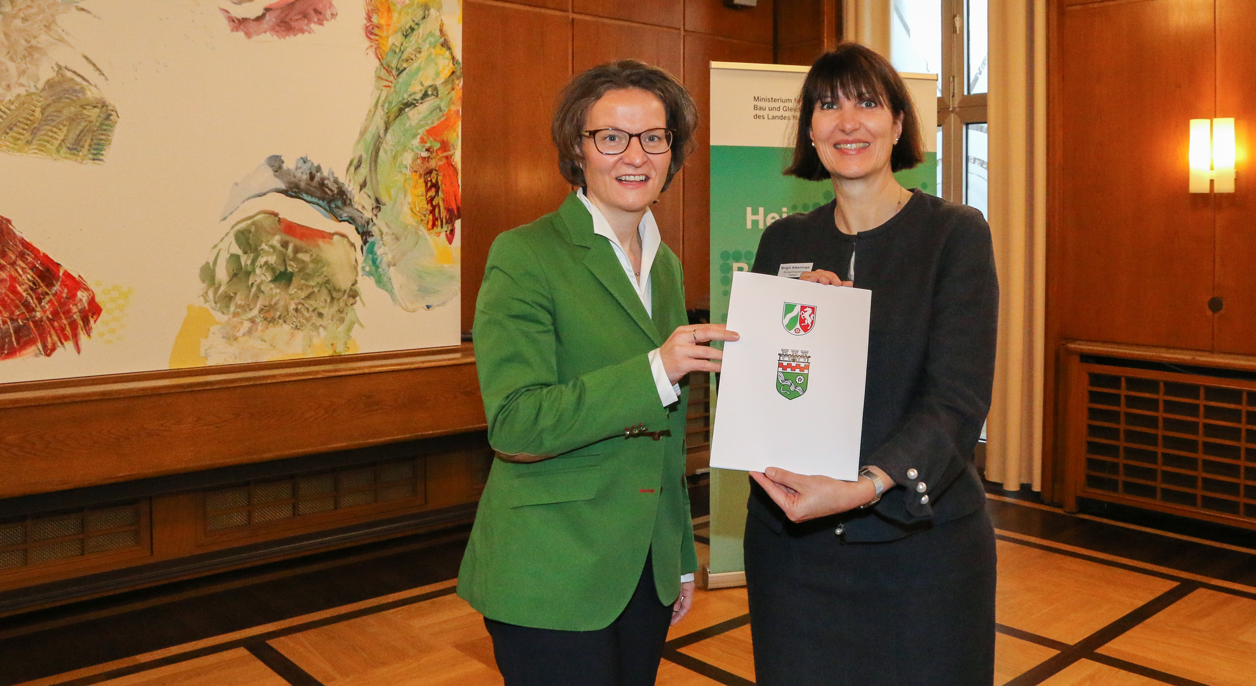 Ministerin Ina Scharrenbach übergibt Bürgermeisterin Birgit Alkenings den Bewilligungsbescheid.