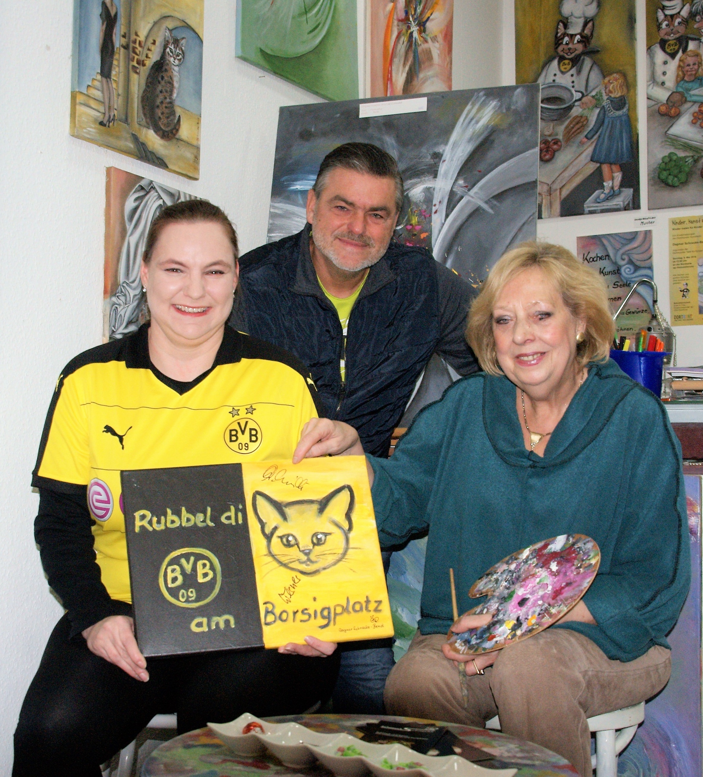 Stephanie Schneider (links) hat das Bild "Rubbeldikatz am Borsigplatz" ersteigert. Mit ihr freuen sich Bernd Uhlenbruck (IN-Stadtmagazine) und die Künstlerin Dagmar Schnecke-Bend (Foto: Rüdiger Beck).