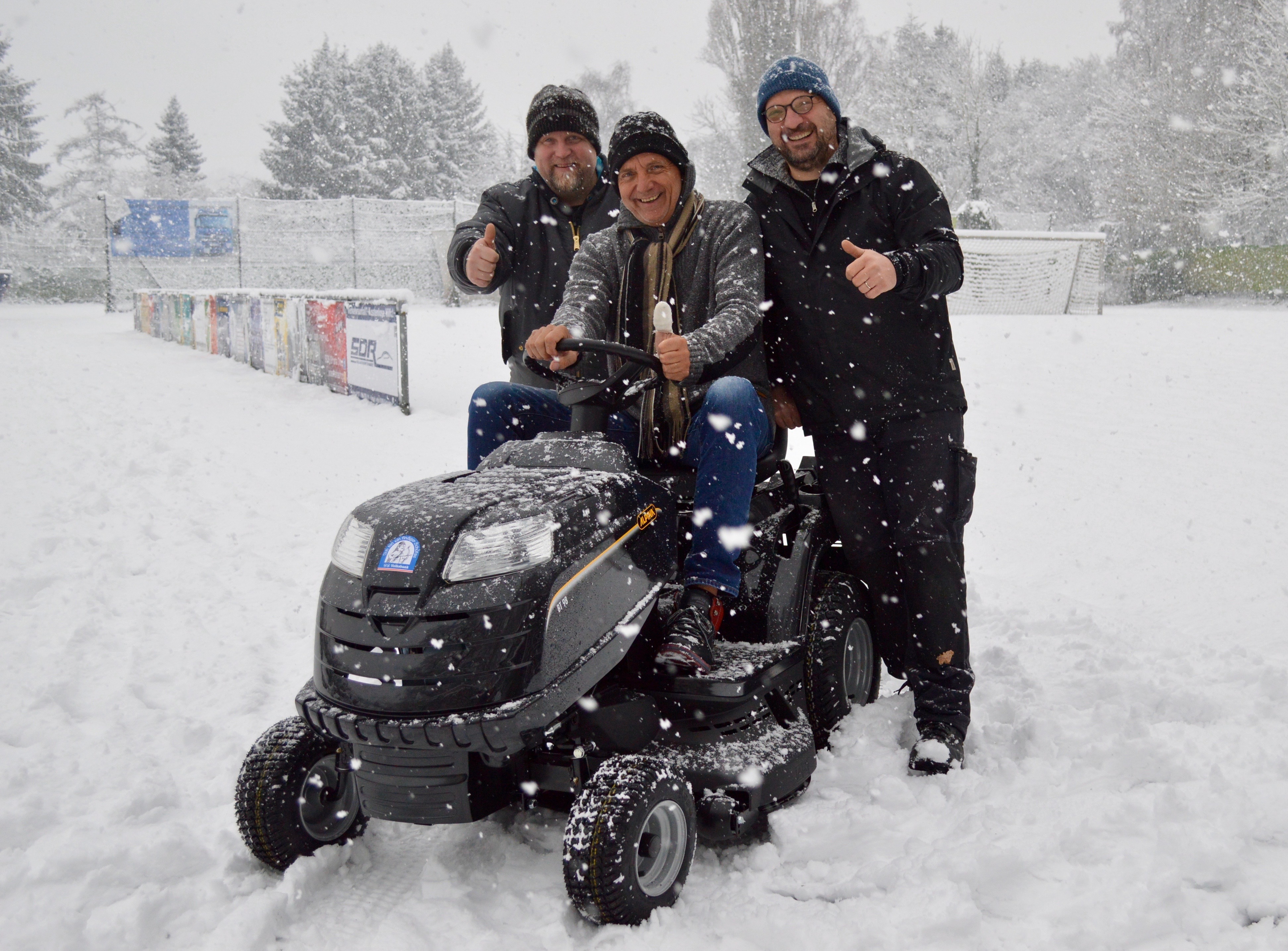 Über den neuen Aufsitz-Rasenmäher freuen sich im dichten Schneetreiben (v.l.) TBS-Mitglied Mika Puhakka, der stellvertretende Vorsitzende Siegfried Jahr und Dieter Blum, technischer Geschäftsführer des Vereins. Foto: RuhrText