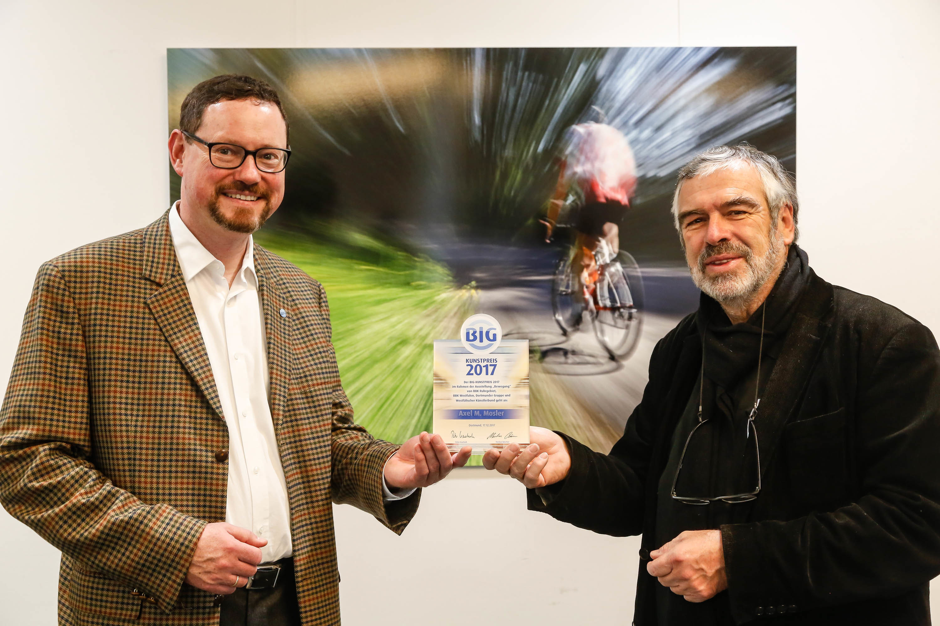 Markus Bäumer (l.), stellvertretender Vorstandsvorsitzender der BIG direkt gesund, überreichte den BIG-Kunstpreis 2017 an Axel M. Mosler. Im Hintergrund die ausgezeichnete Fotografie „Bewegung“ des Preisträgers. (Abdruck honorarfrei)