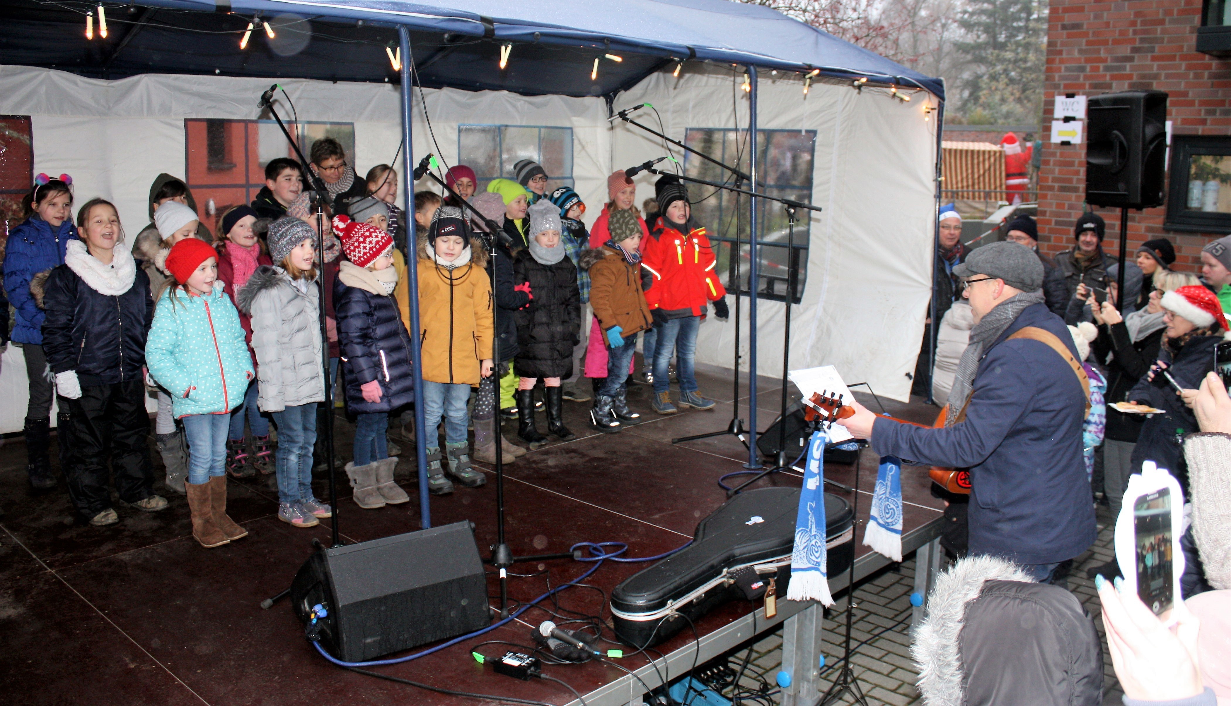 Auch viele Kinder überraschten die zahlreihen Besucher mit Weihnachtsliedern, -geschichten und -gedichten. Hier greift Martin Rödiger, Schulleiter der Schule am Mattlerbusch, zur Gitarre, um seine Schülerinnen und Schüler zu begleiten.