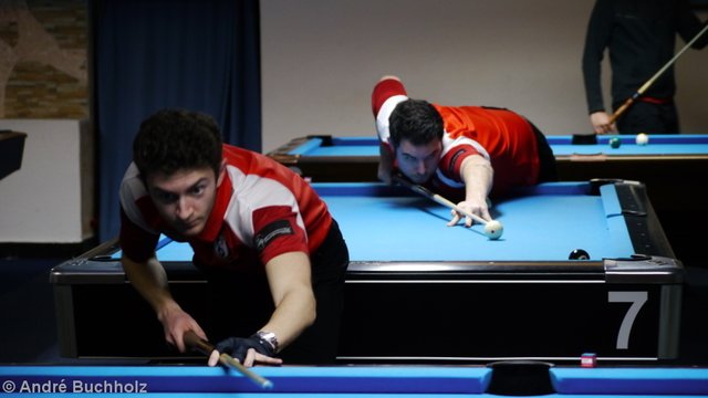 Ilya Bertsun hat abgedrückt und schaut dem Lauf der Kugel nach. Im Hintergrund spielt Emir Secener die Acht.