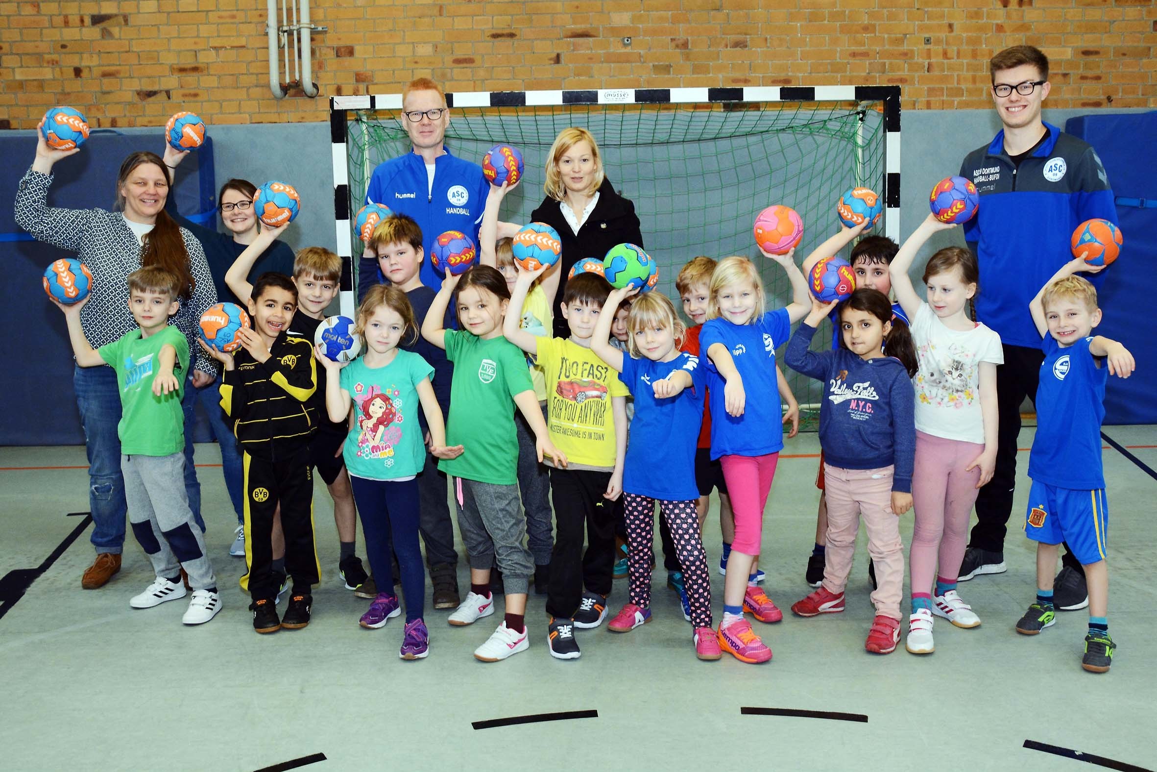Seit dem gestrigen Montag (29.1.) läuft die Handball-Schnupperwoche an der Husener Eichwald-Grundschule. Mit der Klasse 1a freuen sich auch (hinten, v.l.n.r.) Klassenlehrerin Beate Ufert, GL-Lehrerin Richarda Slatosch, Handball-Jugendkoordinator Michael Rieke vom ASC 09, Schulleiterin Stefanie Schönleben-Zimmermann und Trainer Tim Mecklenbrauck auf die neue Handball-AG.