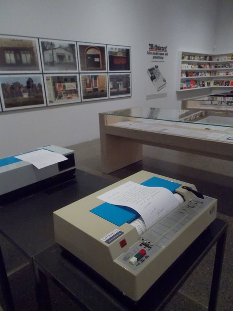 Per Faxgerät kommunizierte Klaus Staeck mit dem Drucker Gerhard Steidl. Im Hintergrund Fotoserie zu Bitterfeld.