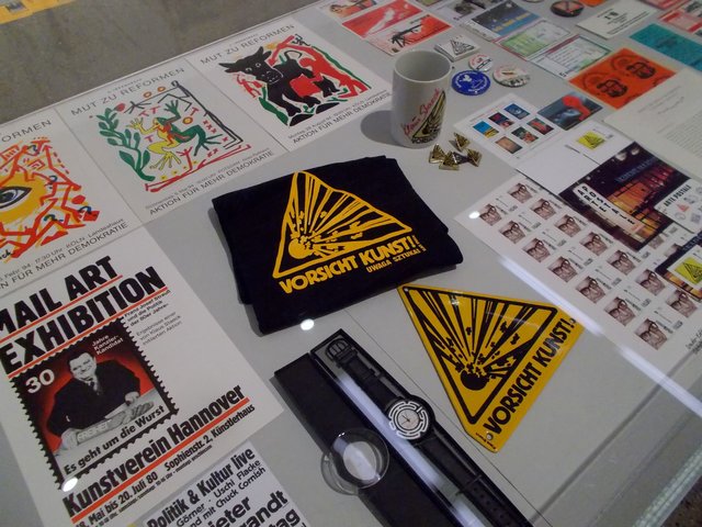 Aufkleber, Briefmarken, Postkarten, Sticker, Becher, T-Shirts, Uhren...Blick in die Ausstellung "Sand im Getriebe", Klaus Staeck im Museum Folkwang.
