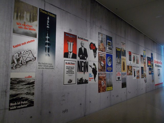 Im Mittelpunkt der Ausstellung stehen Plakate von 1971-2017. Präsentiert auf einer täuschend echt aussehenden Betonwand-Tapete.