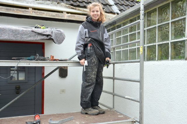 Marie in Arbeitskleidung auf dem Baugerüst.