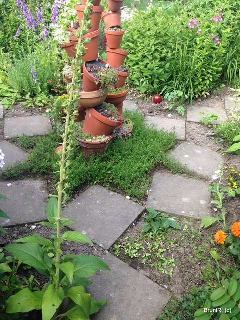 Wie zufällig angeordnete Steinplatten und diese Blumentopfpyramide...