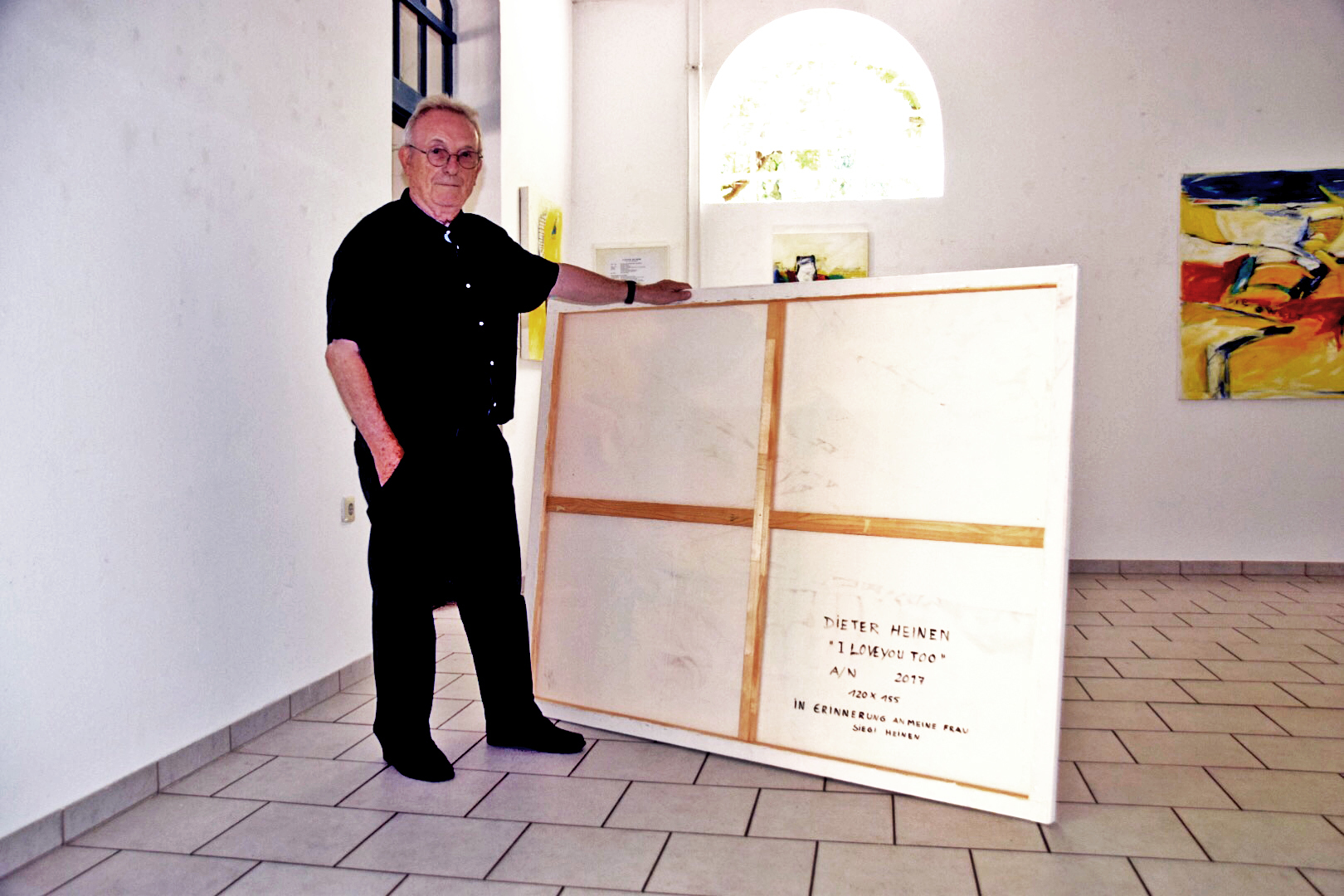 Dieter Heinen hat ein Bild von der Wand genommen und zeigt die Widmung an seine Frau auf der Rückseite.