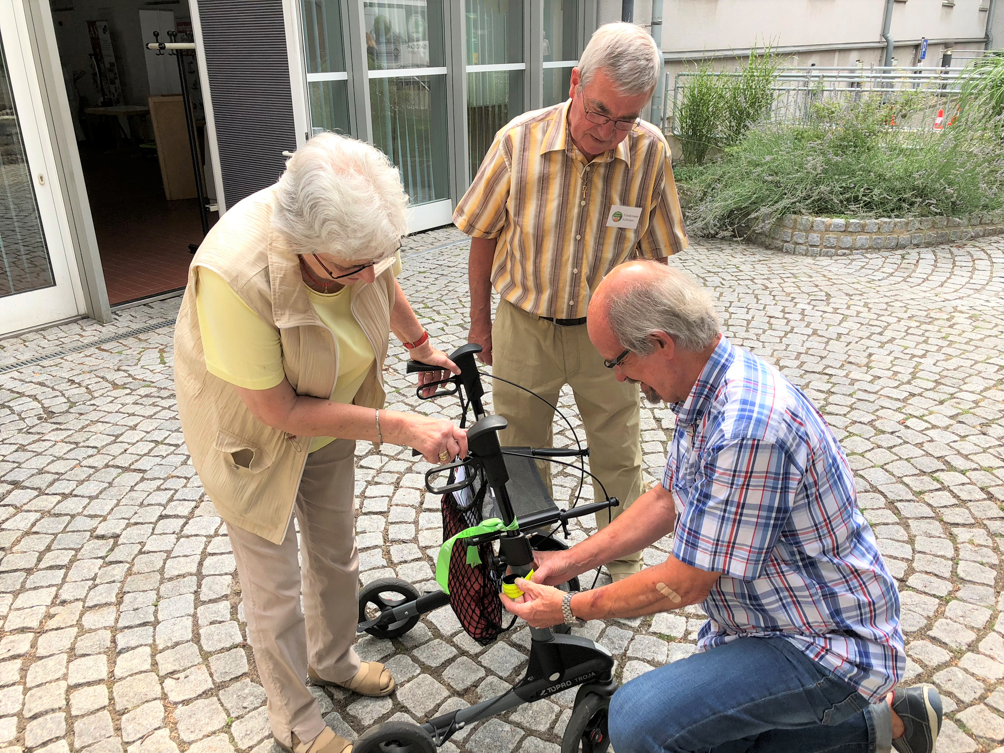 Nach einem Beratungsgespräch mit den Seniorenberatern Klemens Splittgerber (knieend) und Friedemann Schlemm lässt Rollatortag-Besucherin Ursula Bleyer-Feldmann reflektierende Folie an ihrem Rollator anbringen.