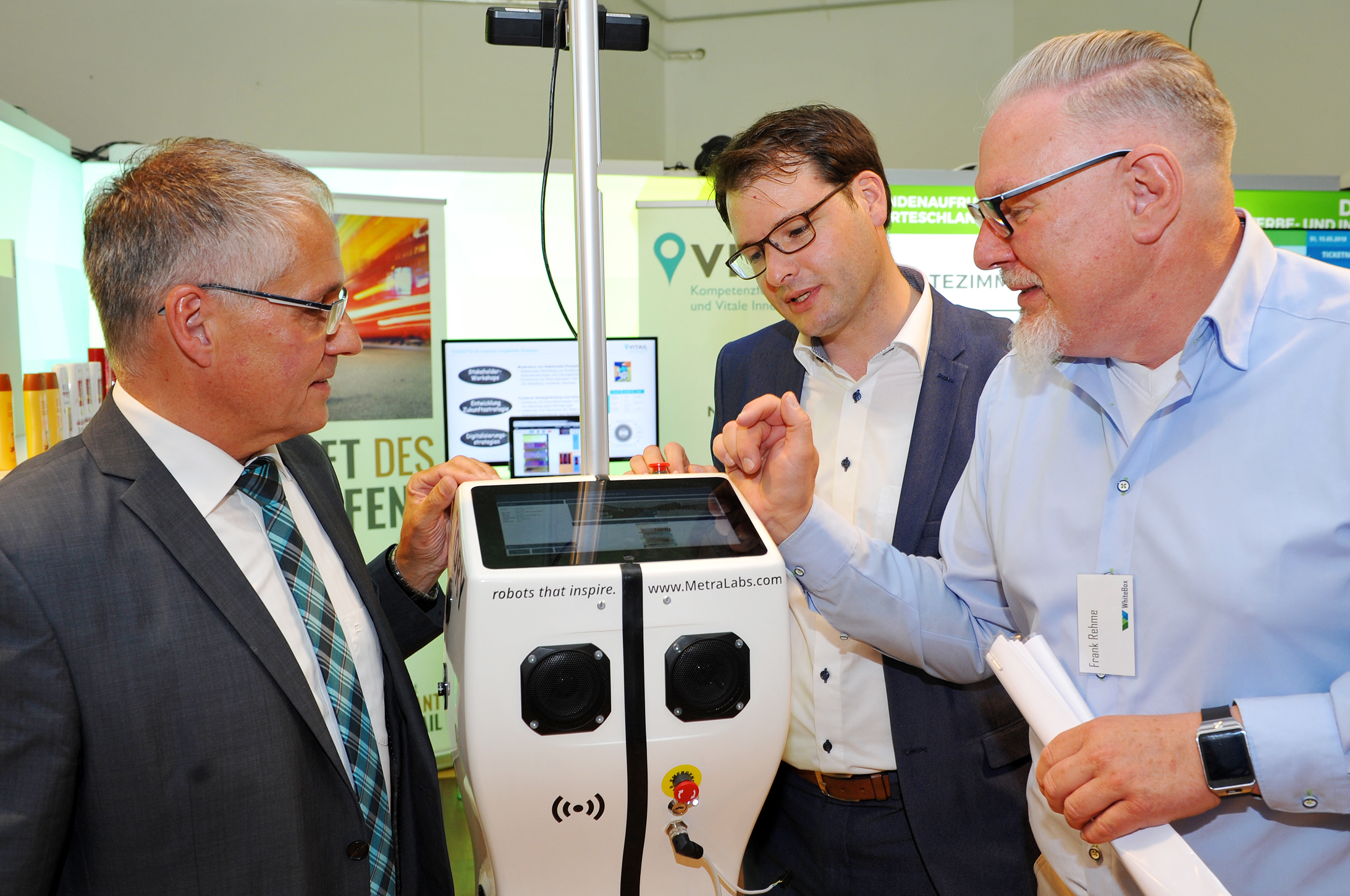 Bürgermeister Frank Schneider (links), Citymanager Jan Christoph Zimmermann (Mitte) und Frank Rehme (von der Future Retail Init.) begutachten TORY, den mobilen Service-Roboter der Firma MetraLabs. Er bewegt sich selbstständig durch ein Geschäft und erfasst dabei den Warenbestand in den Regalen.