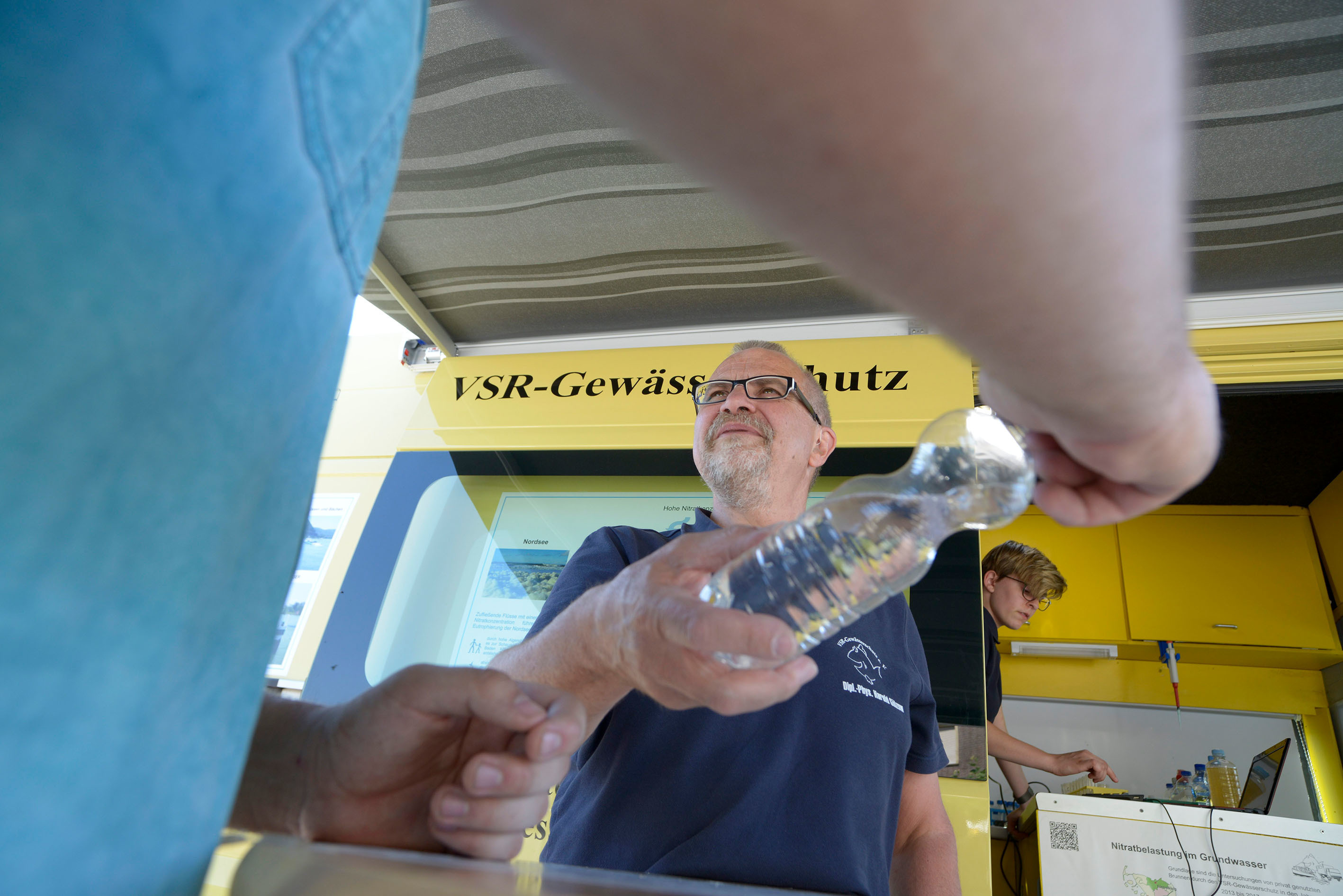 Harald Gülzow (Mitte) nimmt eine Wasserprobe entgegen.