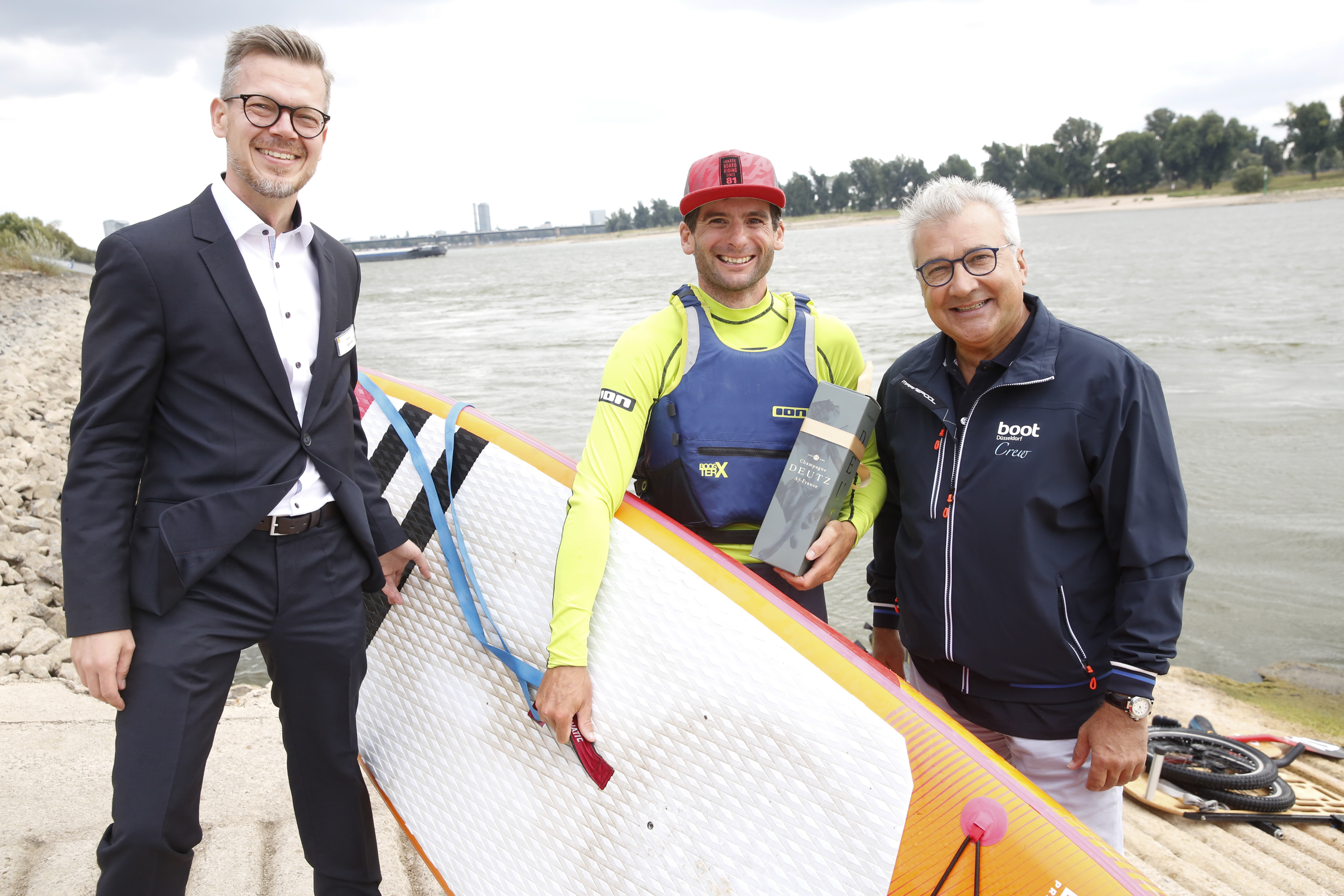 Stefan Koschke, Director des CARAVAN SALON, und boot Chef Petros Michelidakis begrüßten Thomas Oschwald bei der Ankunft in Düsseldorf. Der Schweizer paddelte mit seinem Stand-Up Board 900 Kilometer auf dem Rhein bis zum CARAVAN SALON. Foto: Messe Düsseldorf / Constanze Tillmann
