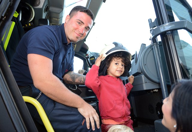 Kinder-Flughafen-Fest auf der Galopprennbahn in Grafenberg. Feuerwehrmann und Brandmeister (Flughafen Feuerwehr ) Gianni Tuttolomondo zeigt Arjan, 2 Jahre, das Schnelleinsatz-Löschfahrzeug (Panther) und setzt ihm den Helm auf.