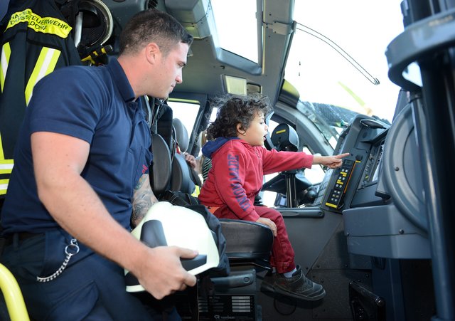 Kinder-Flughafen-Fest auf der Galopprennbahn in Grafenberg. Feuerwehrmann und Brandmeister (Flughafen Feuerwehr ) Gianni Tuttolomondo zeigt Arjan, 2 Jahre, das Schnelleinsatz-Löschfahrzeug (Panther) und setzt ihm den Helm auf.