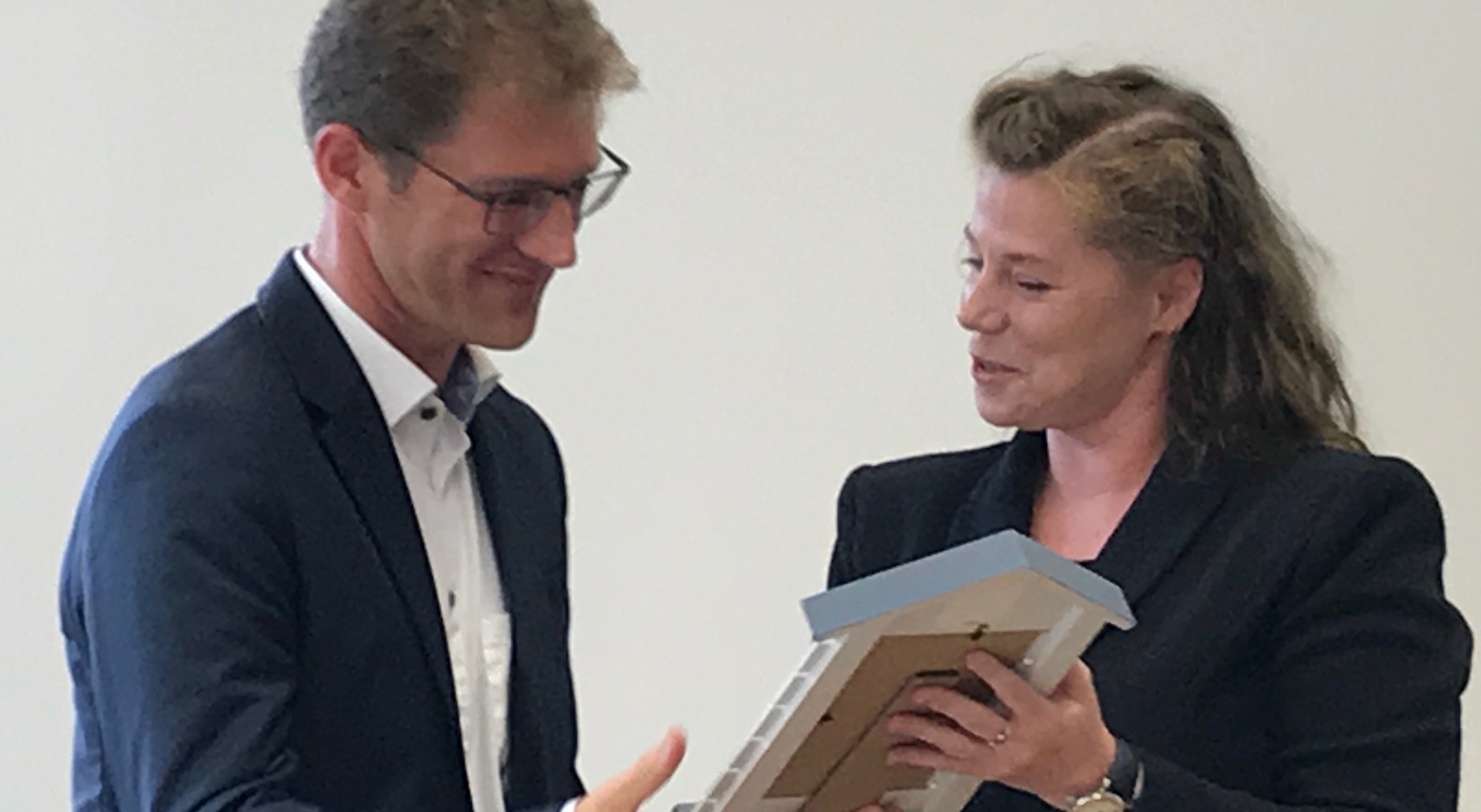 Ein Geschenk mit hohem Symbolwert: Schuldezernentin Katrin Höffken überreicht Lars Schnor ein Leuchtturm-Bild.