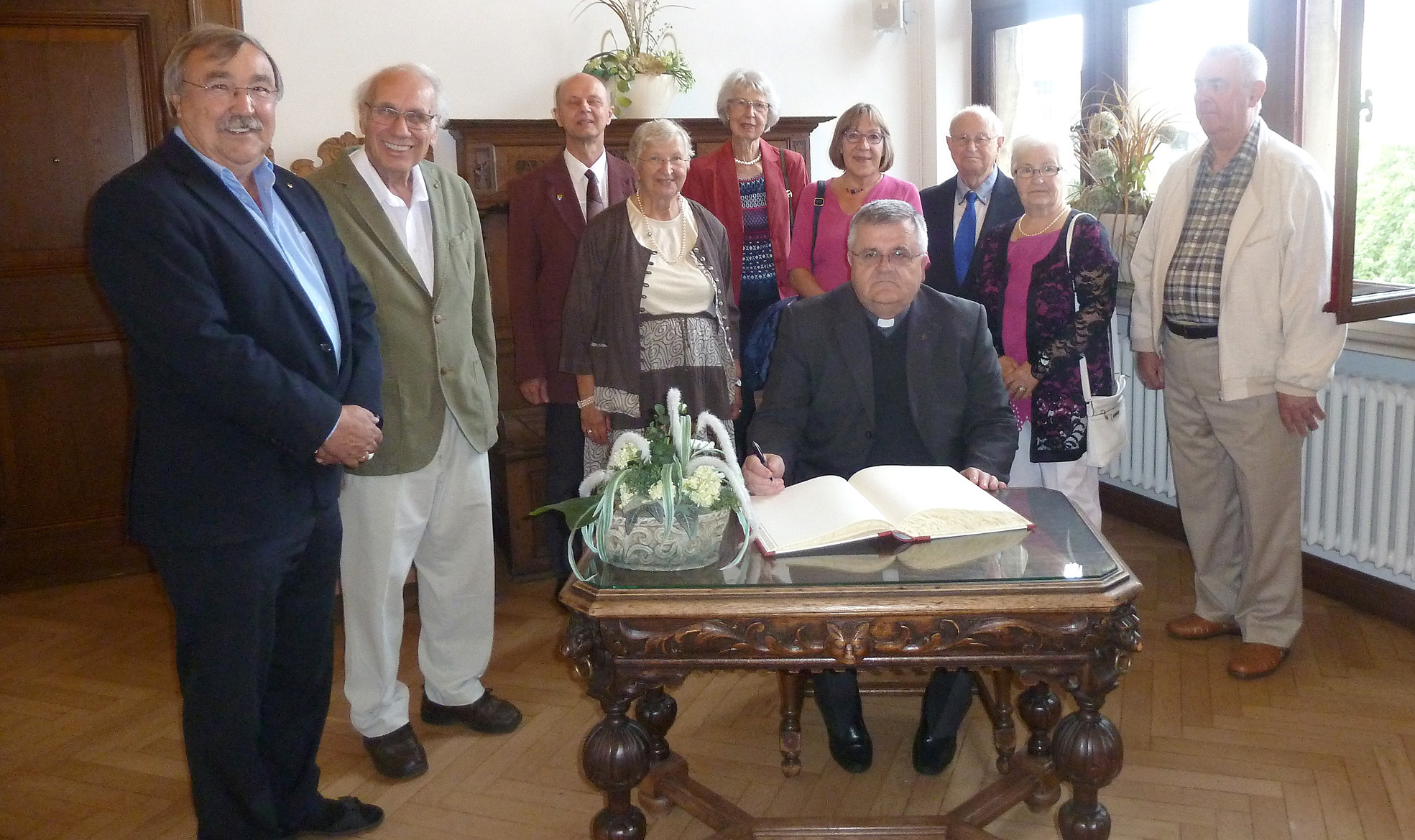 Prof. Tomo Knezevic trägt sich ins Goldene Buch der Stadt ein. Links neben ihm steht Ursula Hölz. Auch ihr Mann Heribert (Zweiter v.l.)und die anderen ehrenamtlichen Helfer der Caritas freuen sich, gemeinsam mit Bürgermeister Manfred Osenger, über den Gast vom Balkan.