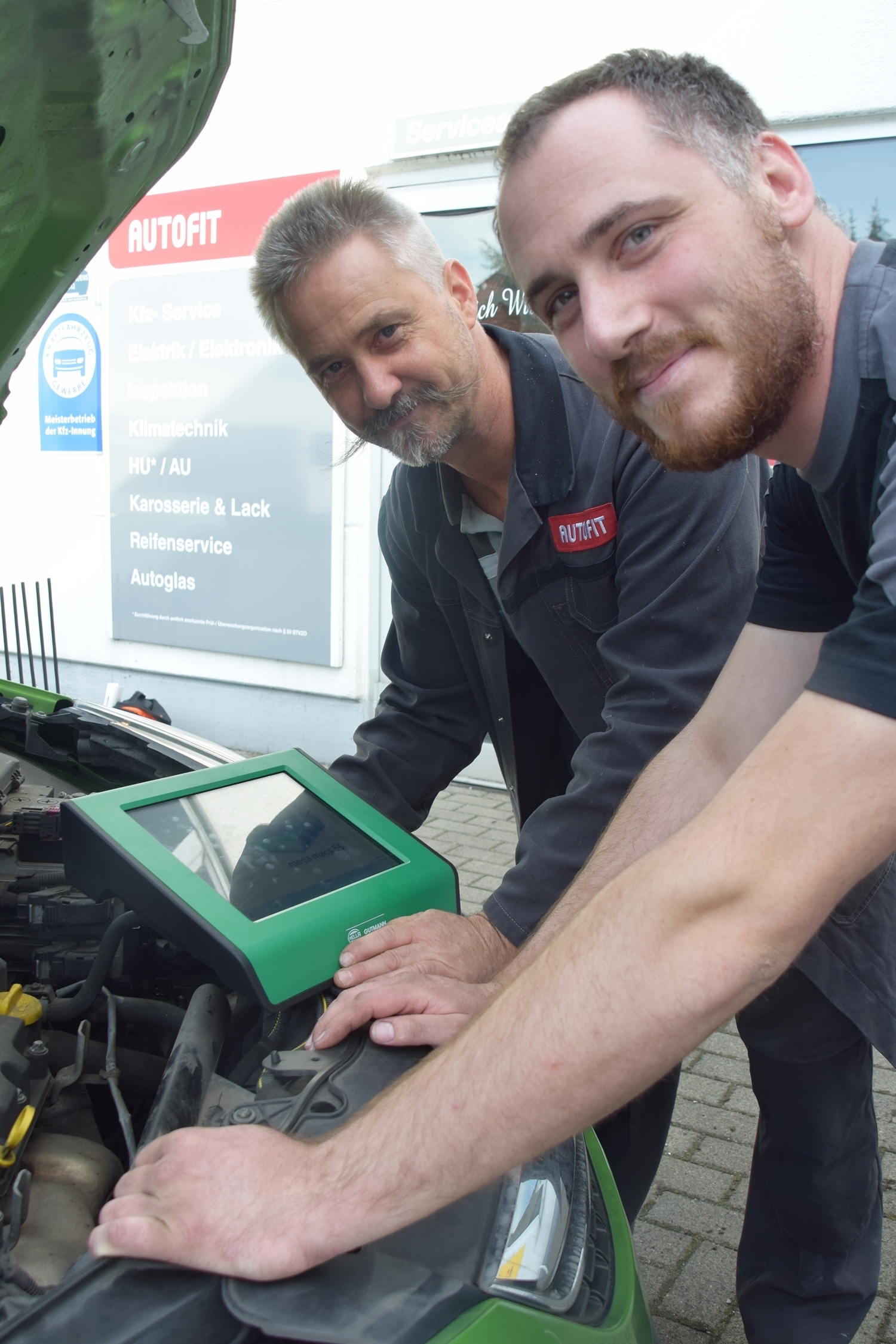 Inhaber Peter Hampf (hinten) und der angehende Kfz Meister Patrick Schulze mit dem neuen Diagnosetester.