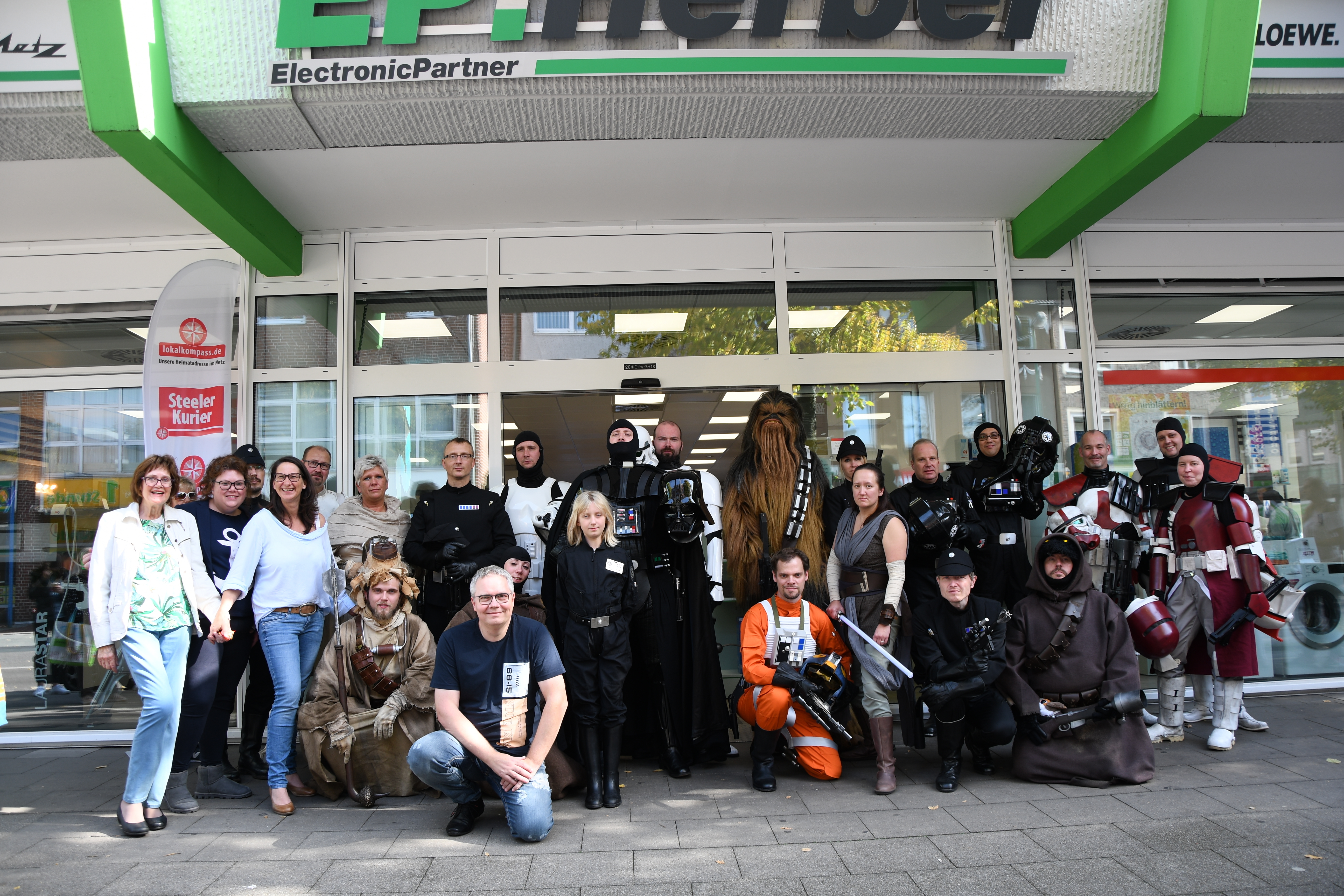Viele Star Wars-Helden, das EP:Herber- sowie das KURIER-Team posierten am Ende des ereignisreichen Star Wars-Tages vor dem Elektronikgeschäft am Kaiser-Wilhelm-Platz 2. EP:Herber-Chef Olaf Zimmermann (2.v.l. vorne kniend) war mit dem Event mehr als zufrieden.