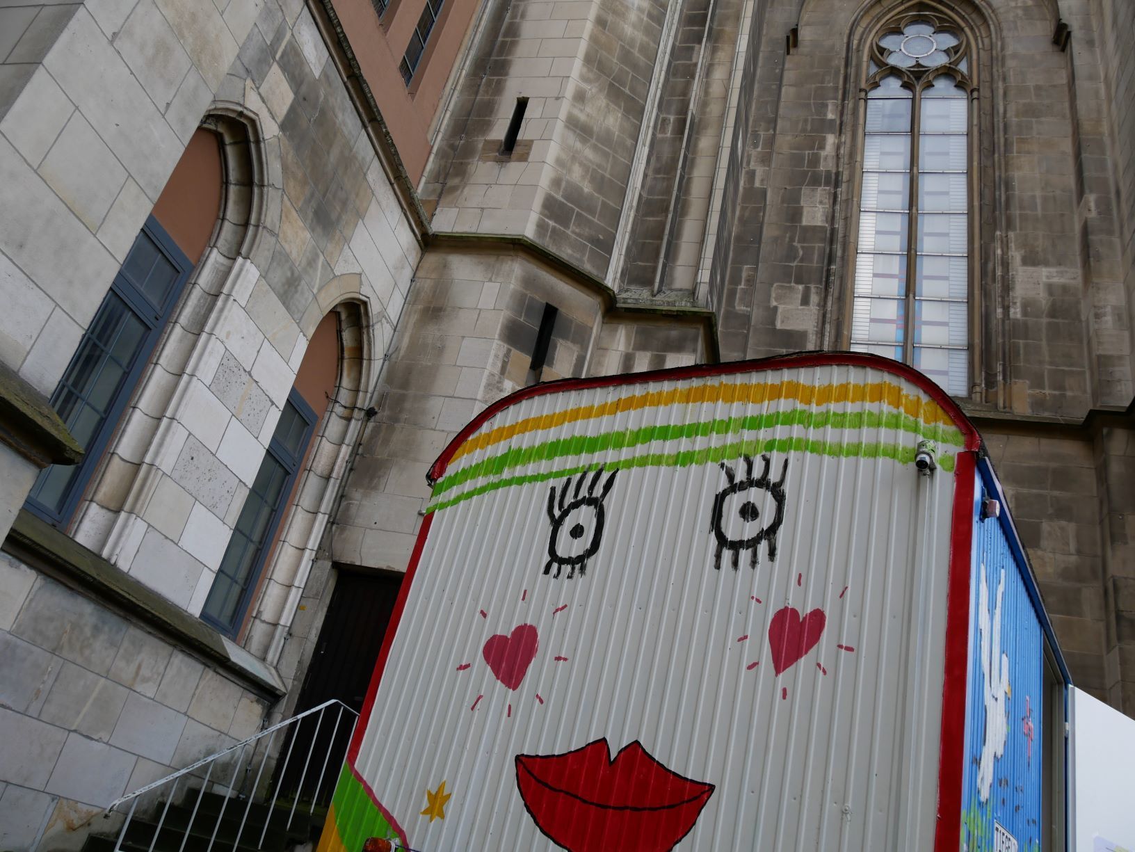 Wer schaut hier so freundlich? Tiegelino - der bunte Bauwagen vor der Kirche St. Gertrud
