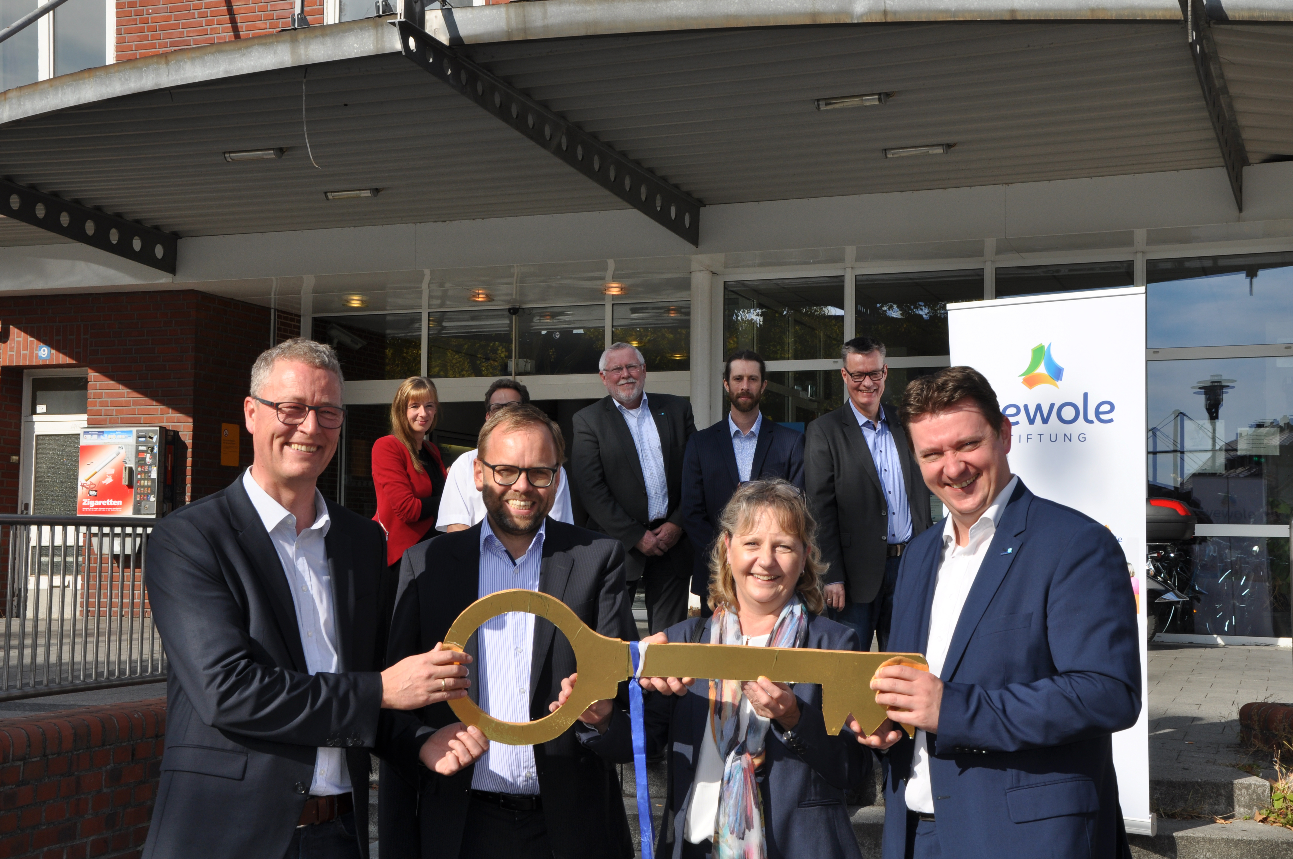 Mit der Schlüsselübergabe von der Deutschen Bahn zur Wewole-Stiftung wurde der Besitzerwechsel am Bahnhofsgebäude offiziell dokumentiert. Die vordere Reihe zeigt (v.l.) Rochus Wellenbrock (Wewole), Carsten Kirchhoff (Bahnflächen-Entwicklungsgesellschaft NRW), Dorothee Wasel (DB Station & Servive) sowie Bürgermeister Rajko Kravanja.