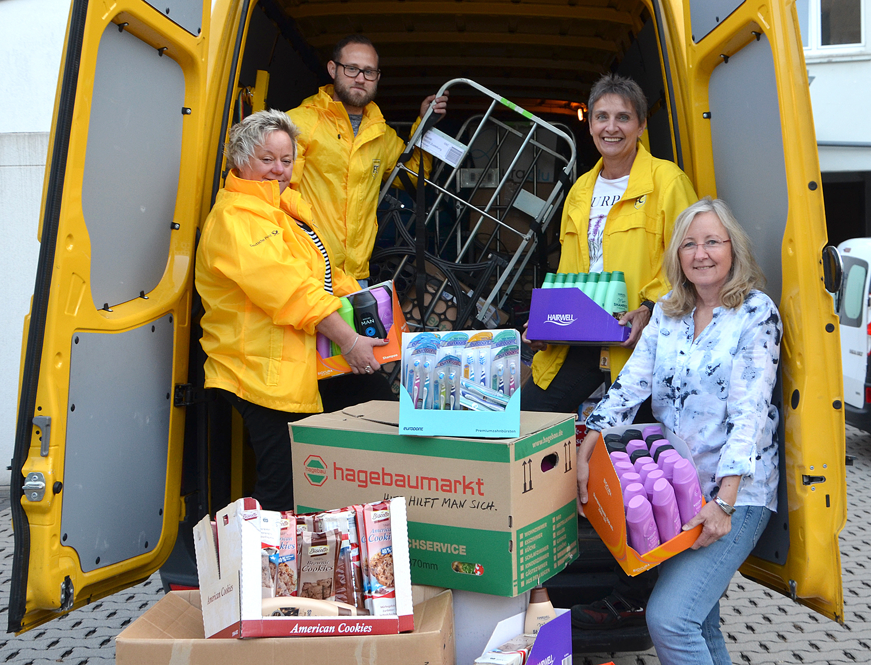Monika Nierhaus, Fabian Deltbarn und Margret Becker haben einen ganzen Transporter voller Spenden an Ilona Ladwig-Henning, Einrichtungsleiterin von Luthers Waschsalon überreicht.