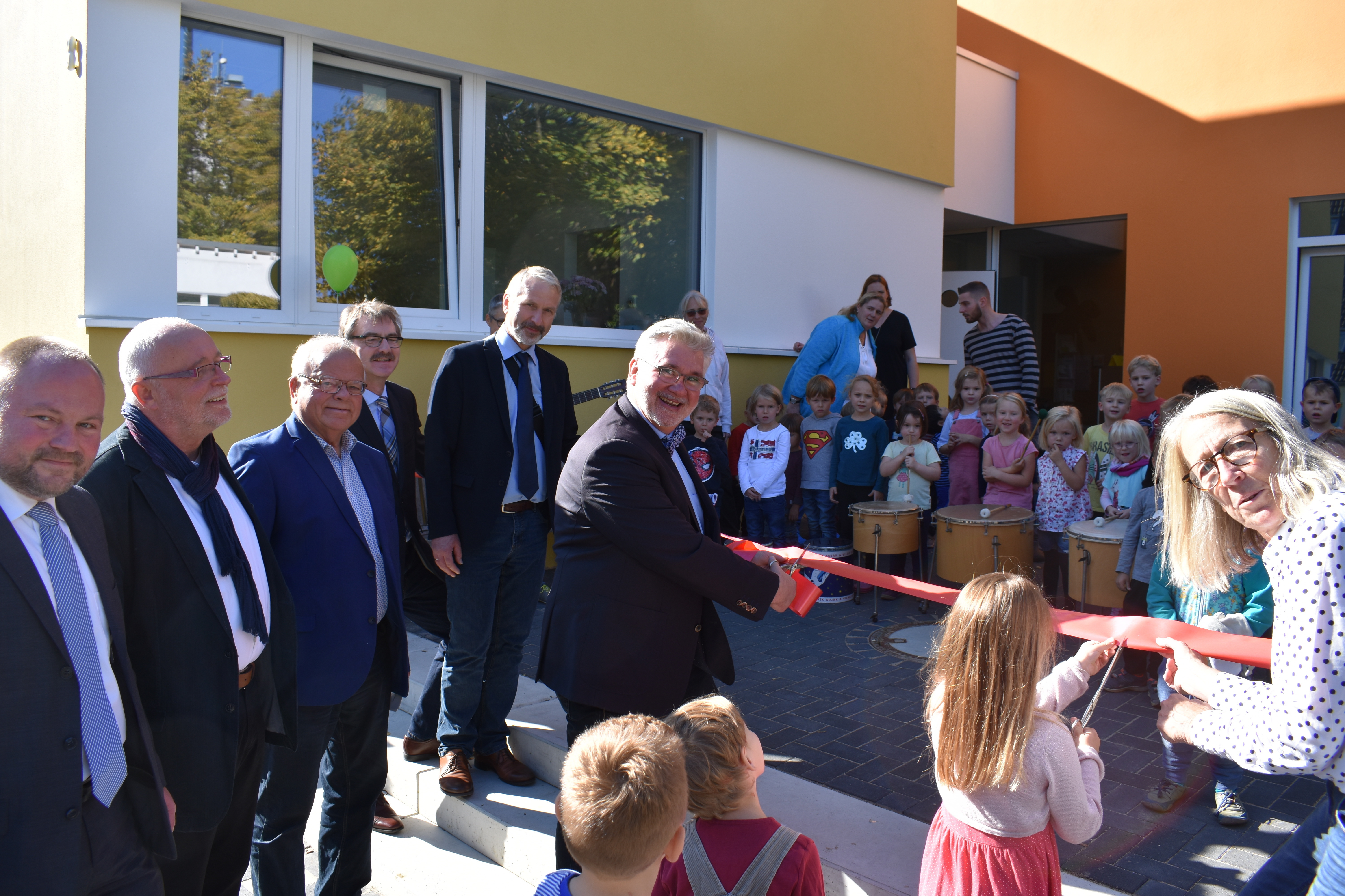 Durchtrenten gemeinsam mit den Kindern das rote Band zur offiziellen Einweihung des Kita-Neubaus: Finanzkirchmeister Jörg Thiede, der stellvertretende Presbyteriumsvorsitzende Rolf Wessels, Bezirksbürgermeister Helmut Kehlbreier, Diakoniepfarrer Andreas Müller, der stellvertretende Geschäftsführer Hartmut Hüttenhoff, Geschäftsbereichsleiter Ulrich Leggereit und Kita-Leiterin Jutta Hartung (von links). Foto: Bernhard Munzel/Diakoniewerk Essen