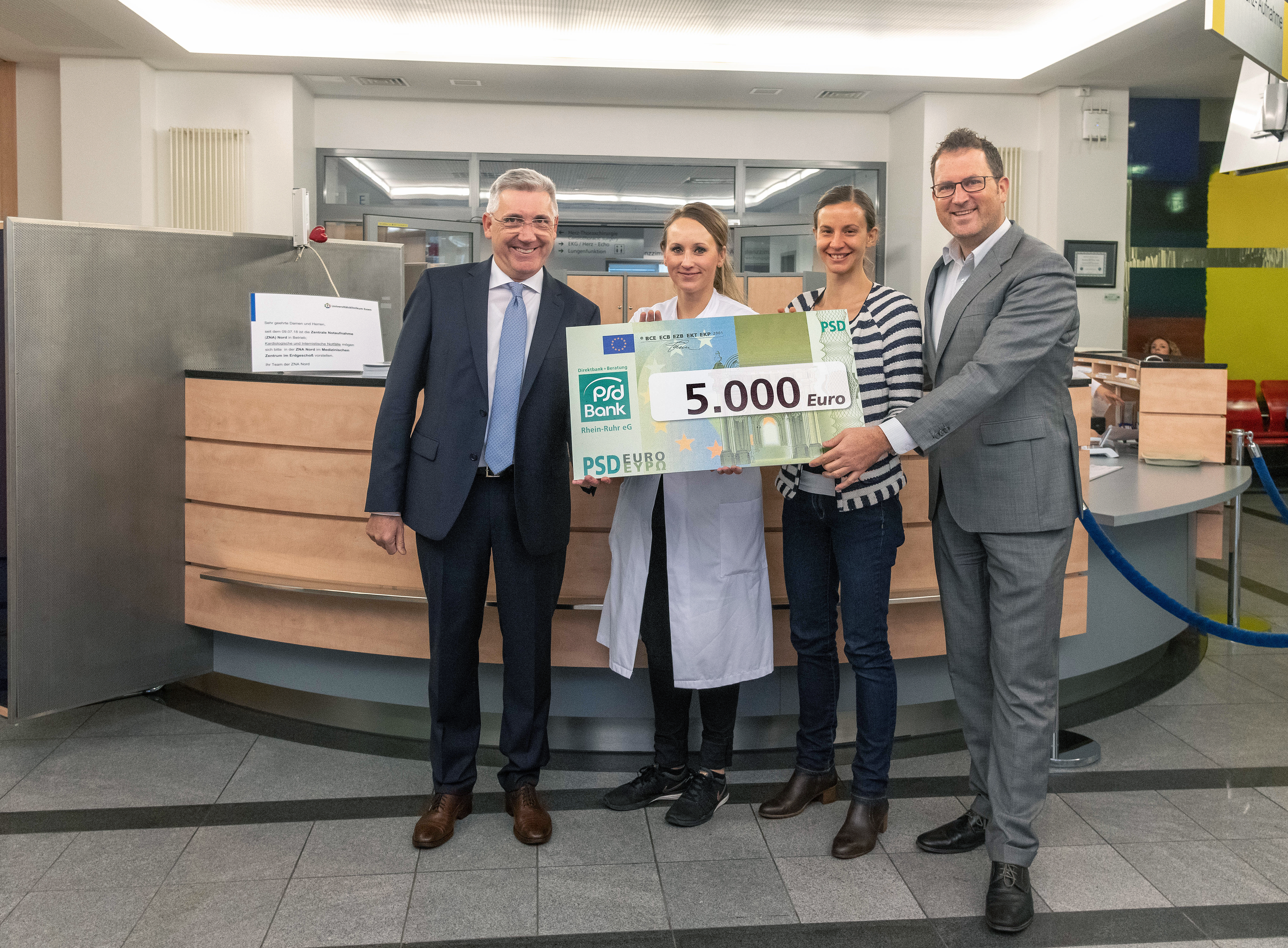 Dr. Martin Münstermann von der PSD Bank Rhein-Ruhr überreicht Dr. Julia Lortz, Oberärztin der Klinik für Kardiologie und Angiologie am Westdeutschen Herzzentrum, Dr. Katrin Paldán, stellvertretende Leiterin der Nachwuchsforscher-gruppe PanAlytics und Jorit Ness, Geschäftsführer der Stiftung Universitätsmedizin den Scheck über 5000 Euro
