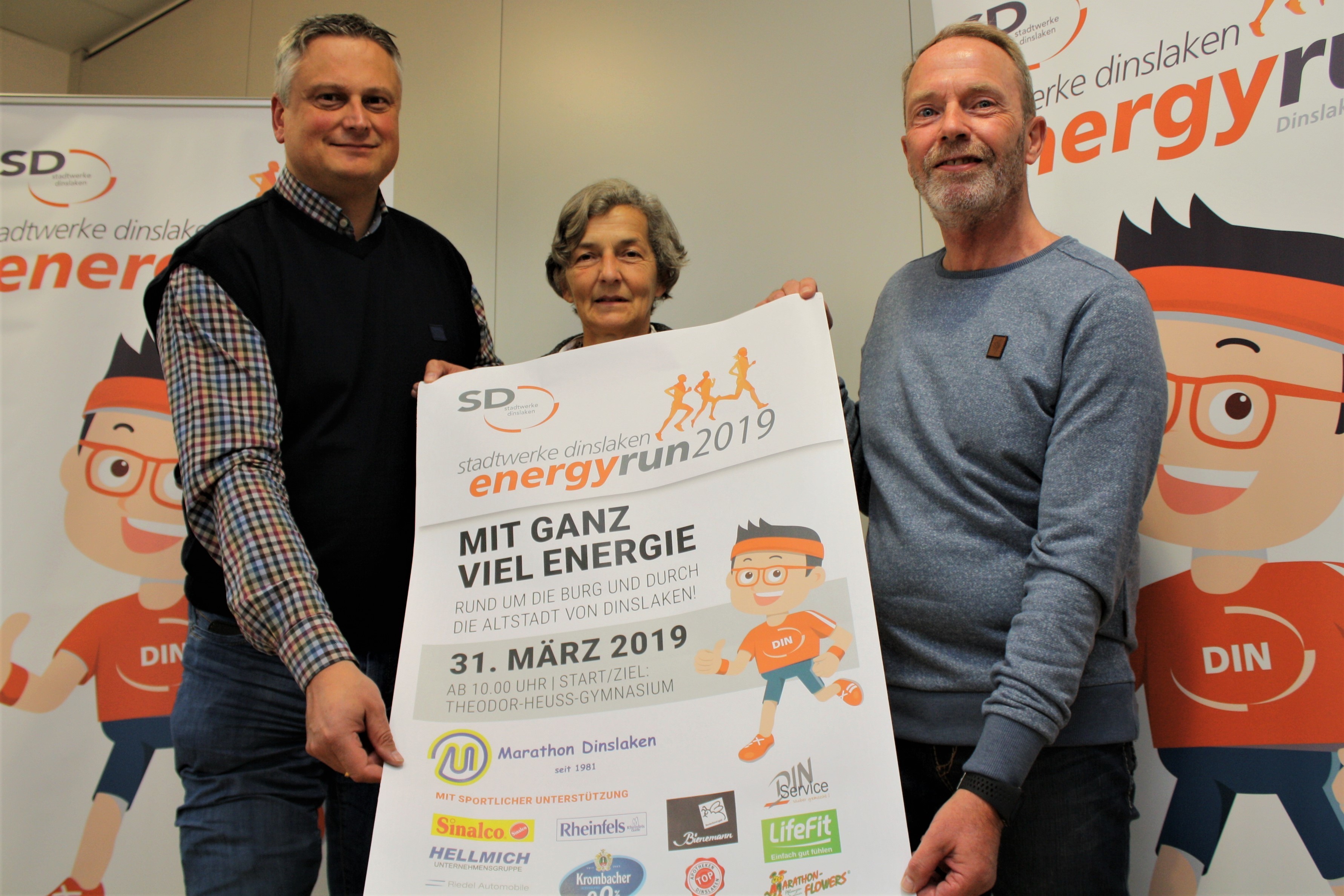 Präsentieren das Veranstaltungsplakat. Von li. Josef Kremer (GF Stadtwerke Dinslaken), Friederike Setzepfandt (Sportwartin Marathon Dinslaken e.V.) und Vorsitzender Manfred Feldkamp.