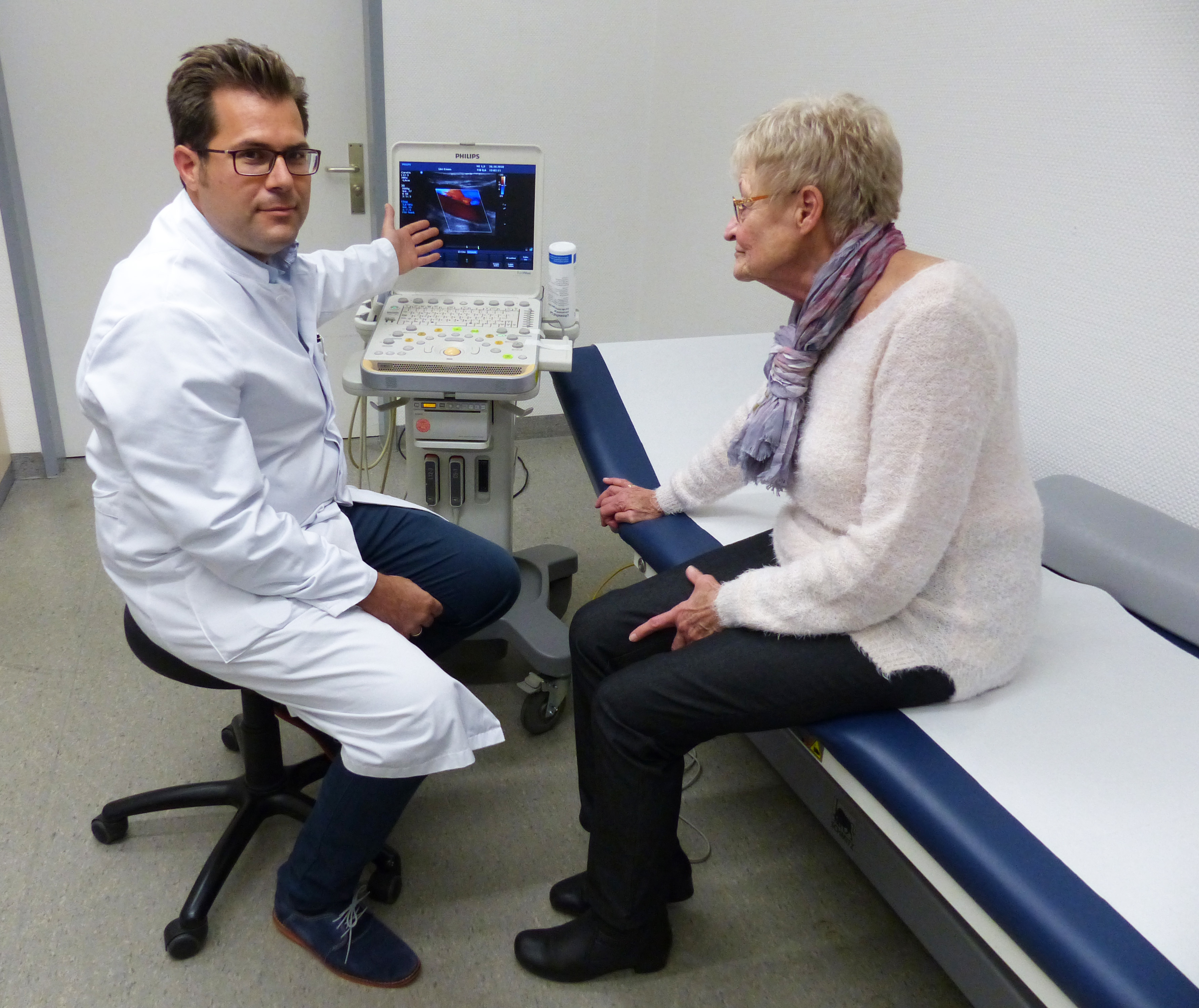PD Dr. Christos Rammos (l.), Oberarzt der Klinik für Kardiologie und Angiologie, ist zufrieden mit den Genesungsfortschritten der Patientin Barbara Beyer.