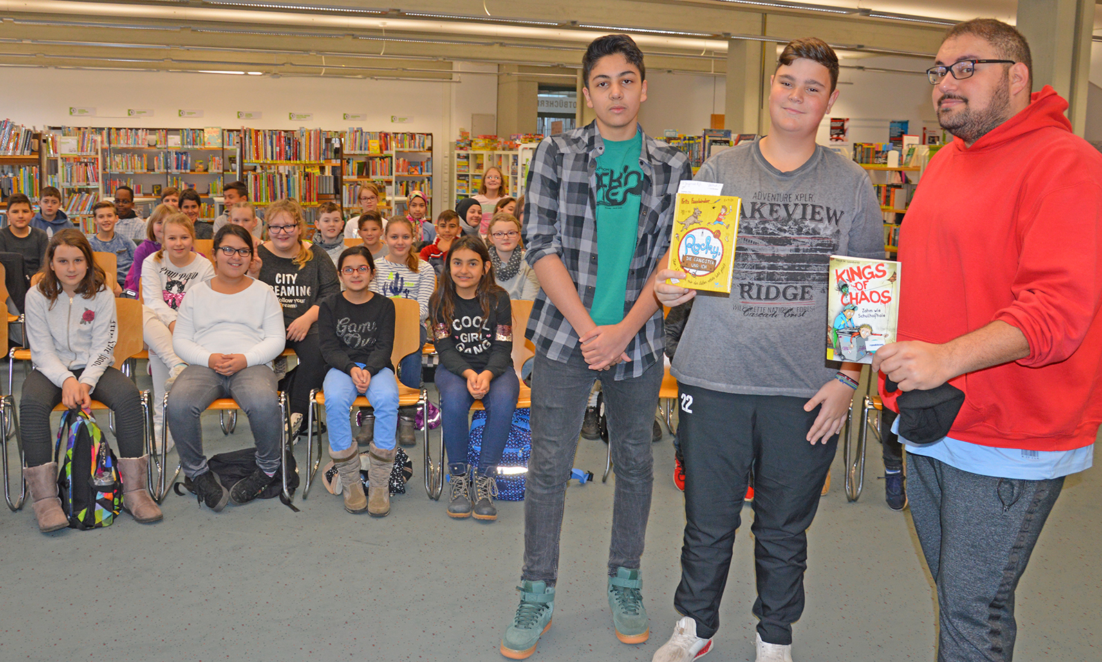 Bora-Ahmet Altun (rechts), Velberter Comedian und Pädagoge, las in der Kinderbücherei in Velbert interessierten Fünftklässlern der Realschule Kastanienallee vor. Unterstützt wurde er dabei von zwei Realschülern der Jahrgangsstufe neun.